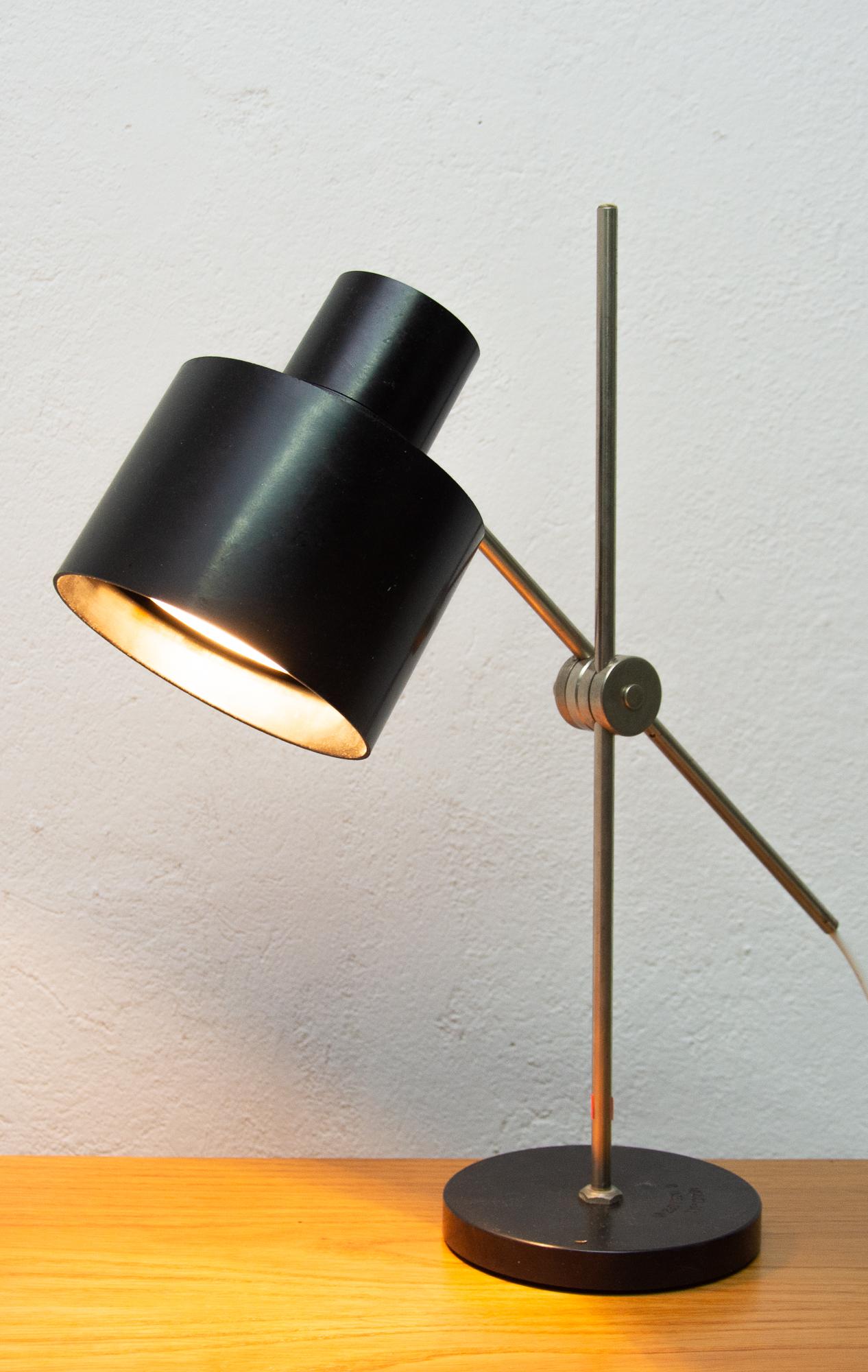 This midcentury table lamp called “commissioner” was made in the former Czechoslovakia in the 1960s. It was made by Elektrosvit n.p. company under type 1012 01 and designed by Ján Šuchán.
It´s made of black Bakelite, has metal positioning