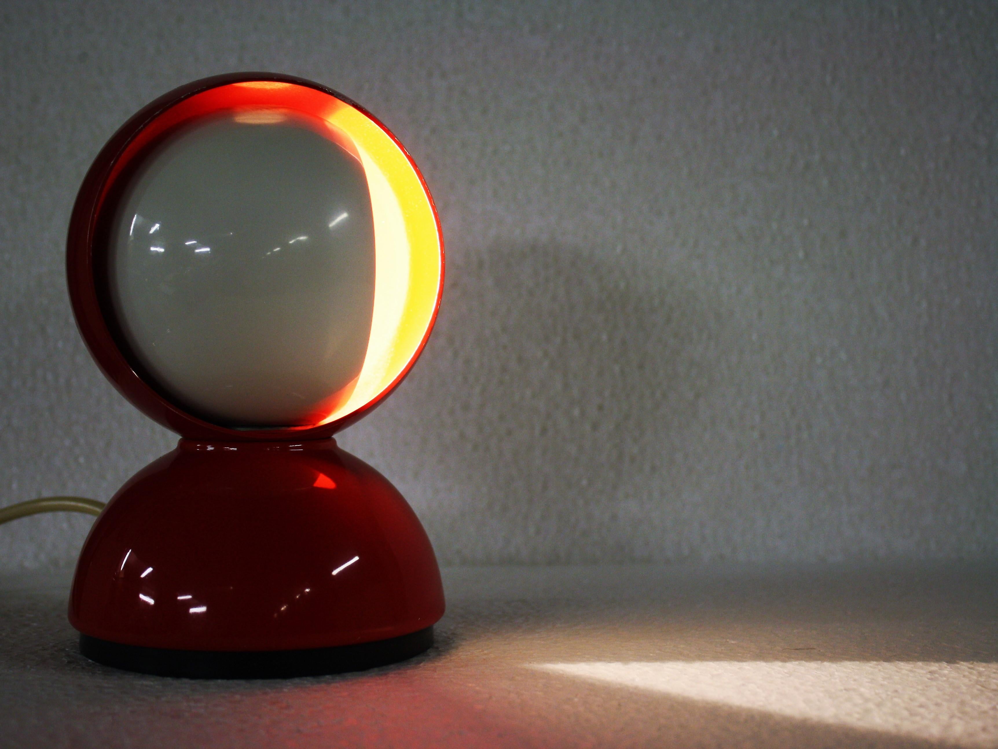 Midcentury red and white table lamp designed by Vico Magistretti for Artemide. 

The lamp is made to resemble an eclipse, thanks to it's smart design it emits a lovely light effect. 

Tested and ready to use with a E14 light bulb.

1970s -