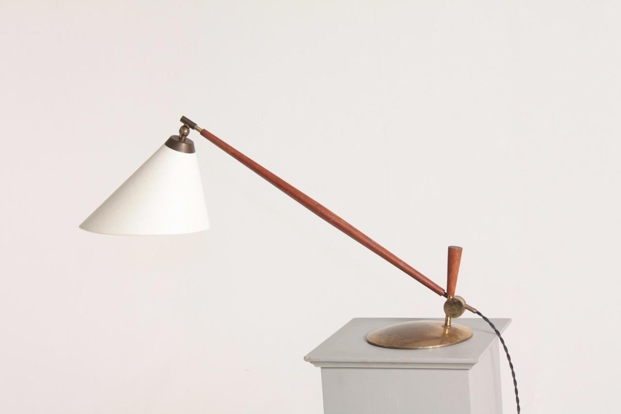 Adjustable table lamp in brass and teak. Designed by Th. Valentiner made by Poul Dinesen in 1950s. Made in Denmark.