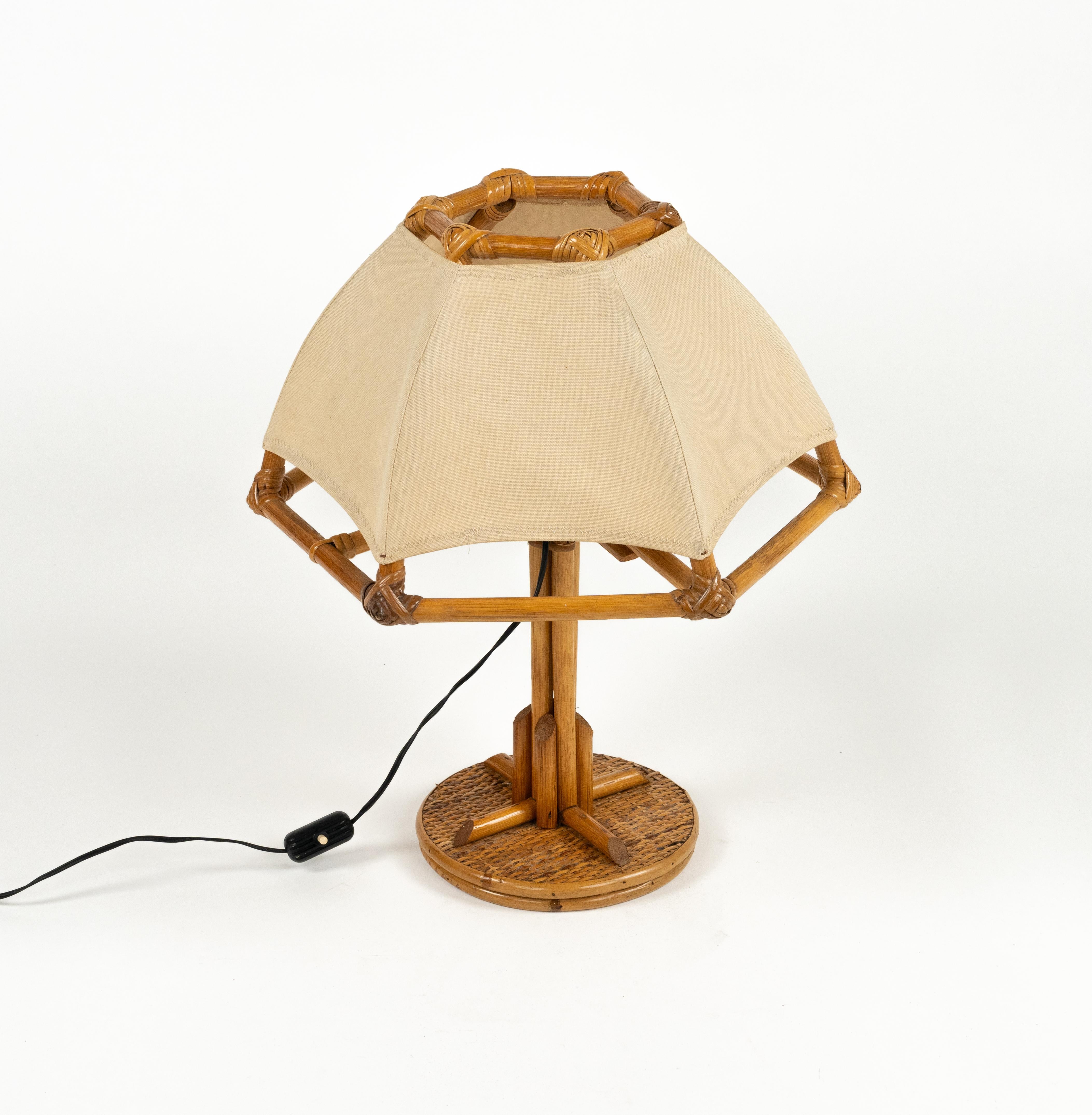 Wunderschöne sechseckige Tischleuchte aus der Mitte des Jahrhunderts aus Rattan und Bambus mit weißem Stoffschirm.  

Hergestellt in Italien in den 1970er Jahren.  

Neue elektrische Anlage europäischen Stecker (funktioniert außerhalb der EU mit