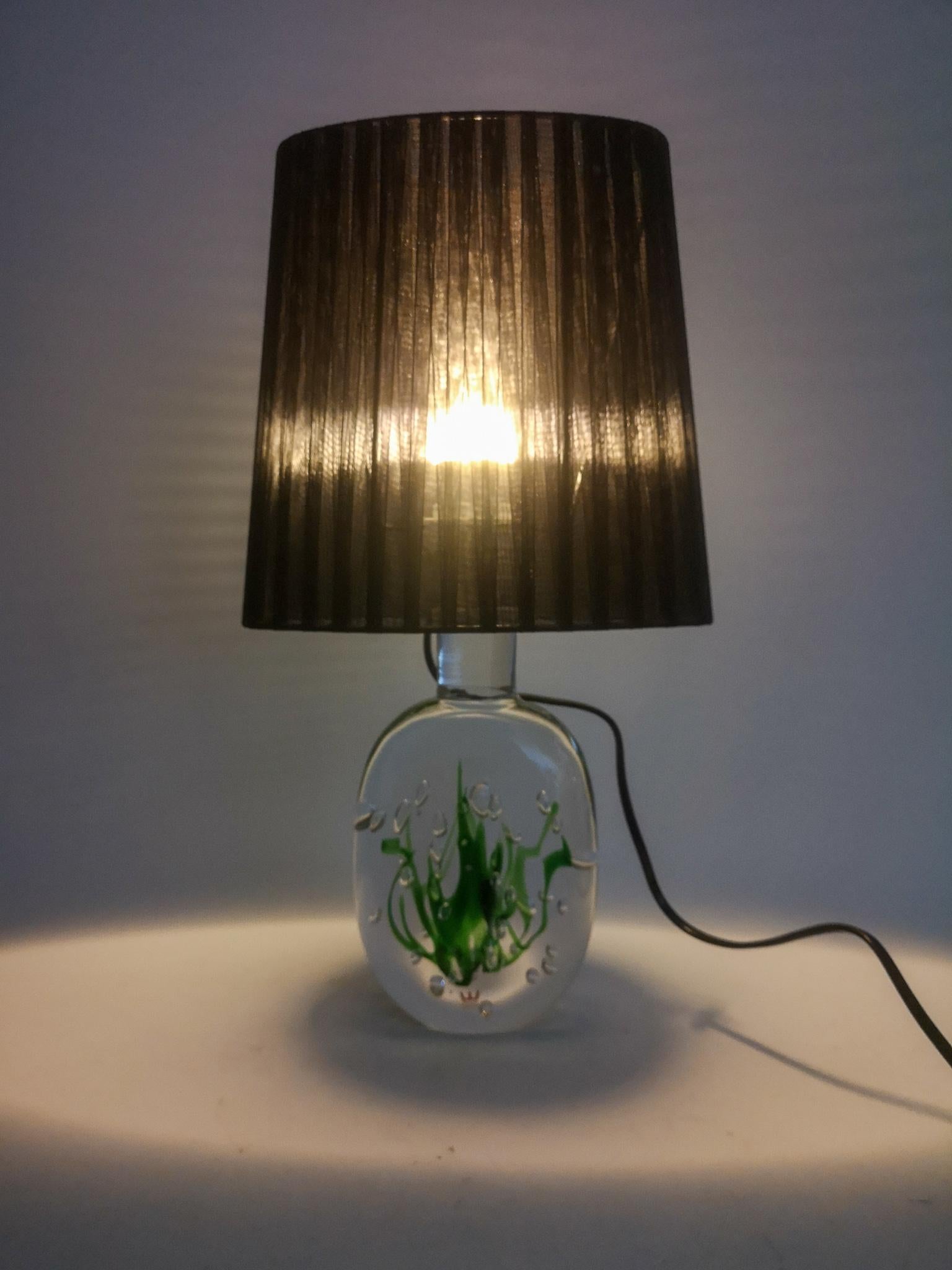 Merveilleuse lampe de table produite en Suède à l'usine Kosta. Conçu par Vicke Lindstrand. 
Cette lampe est en verre transparent avec des algues à l'intérieur. Cette pièce emblématique fonctionne parfaitement en tant que lampe et créera une