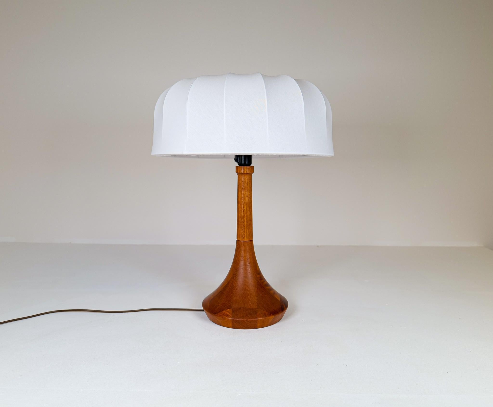 This stunning large table lamp made in solid teak was created by the Danish designer Lisbeth Brams in the 1960s Denmark. 
The exclusiveness int this lamp shows not only in its design but also in the way the quality of the teak has been chosen.