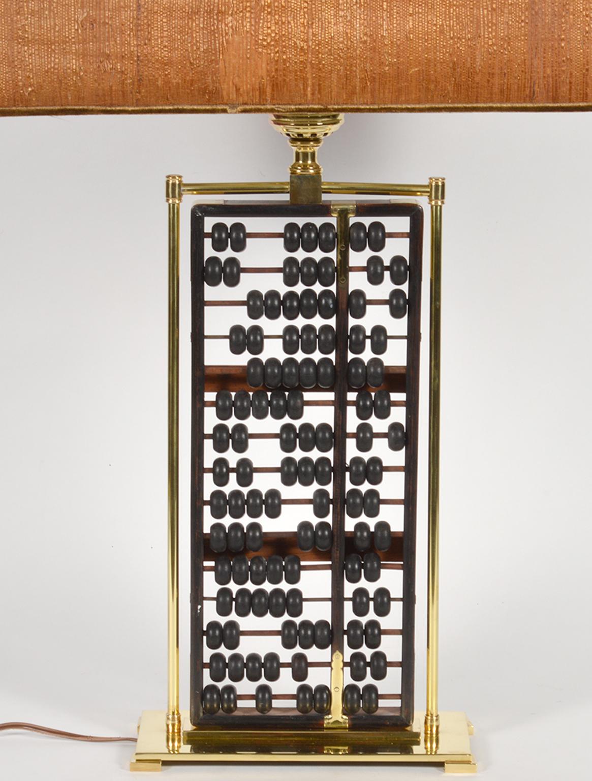 Standing 31.5 inches high including the original bark covered shade this lamp consists of an antique Chinese abacus incorporated in solid brass framing and resting on a rectangular footed brass base. The lamp retains its original conical milk glass