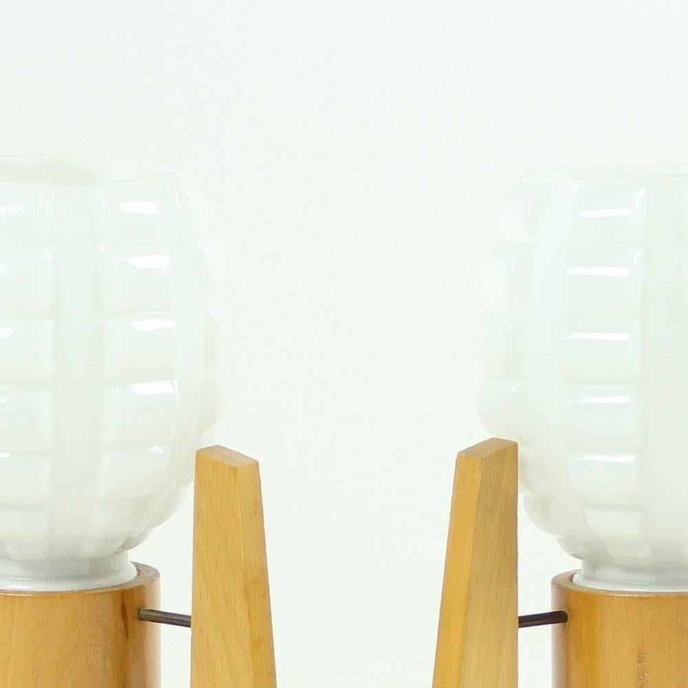 Set of 2 table lamps from Mid-Century Modern era of Czechoslovakia. The lamps are made of stylish white opeline glass shiels with wooden base. Design is very typical for the 1960s era with great details. Ideal combination for an interesting interior