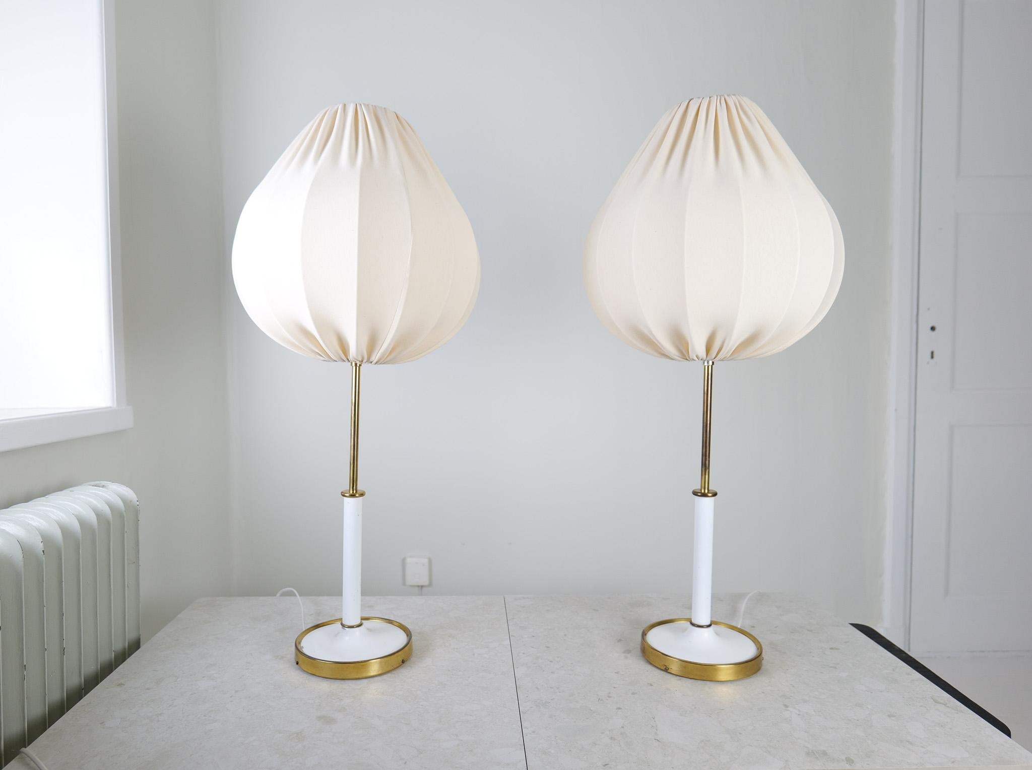 Cette paire de lampes de table iconiques, modèle G2326, a été conçue par Josef Frank et produite par Svenskt Tenn en Suède. Le modèle est réalisé en laiton et en métal laqué. Ceux-ci ont des abat-jour en coton en forme de tulipe et sont fabriqués en