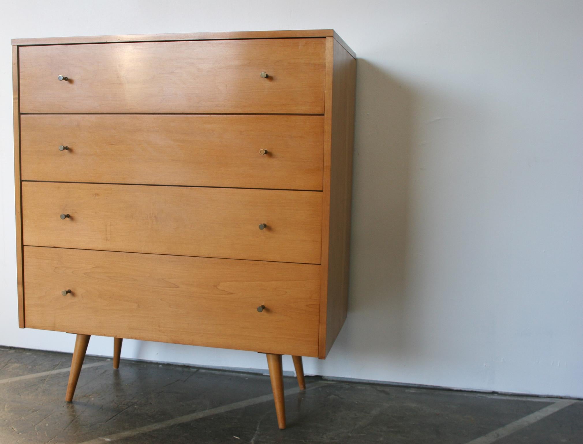 Beautiful midcentury tall dresser 4-drawer dresser by Paul McCobb circa 1950 Planner Group #1501 with 4 center drawers. Solid maple construction has a Beautiful Blonde Lacquered finish. All original Brass Cone pulls sits on 4 Solid Maple Tapered