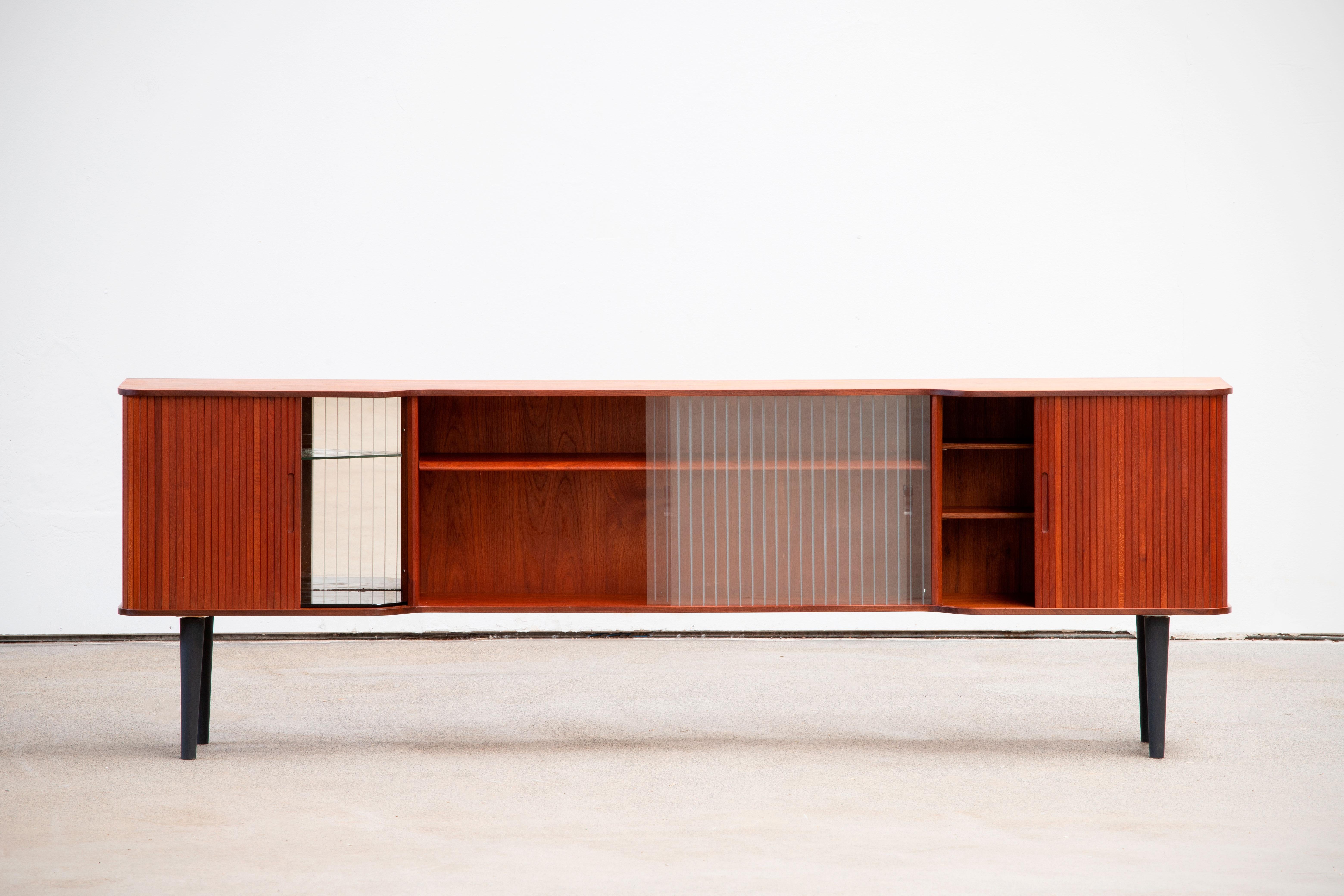 Midcentury teak sideboard with tambour doors from the 1960s. It is a shining example of the form and function synonymous with furniture of this era. It has is all; well-built, great design and heaviness. four sliding doors storage space. The minimal