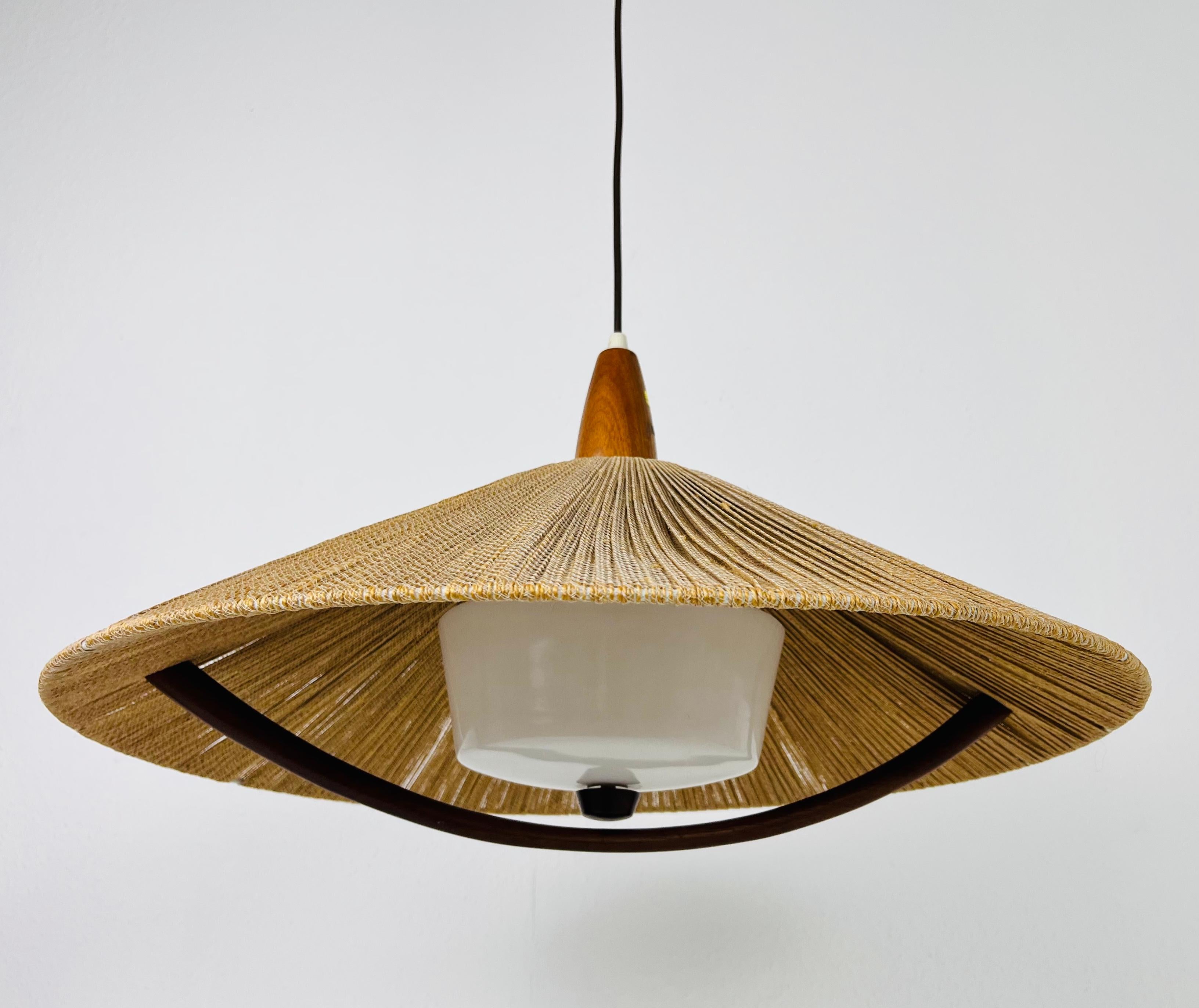 A wonderful teak hanging lamp made in the 1960s by Temde in Switzerland. It is fascinating with its rare lamp shade, which gives the lighting a wonderful japanese design.

The height is adjustable from 30 cm up to 110 cm.

The light requires one E27
