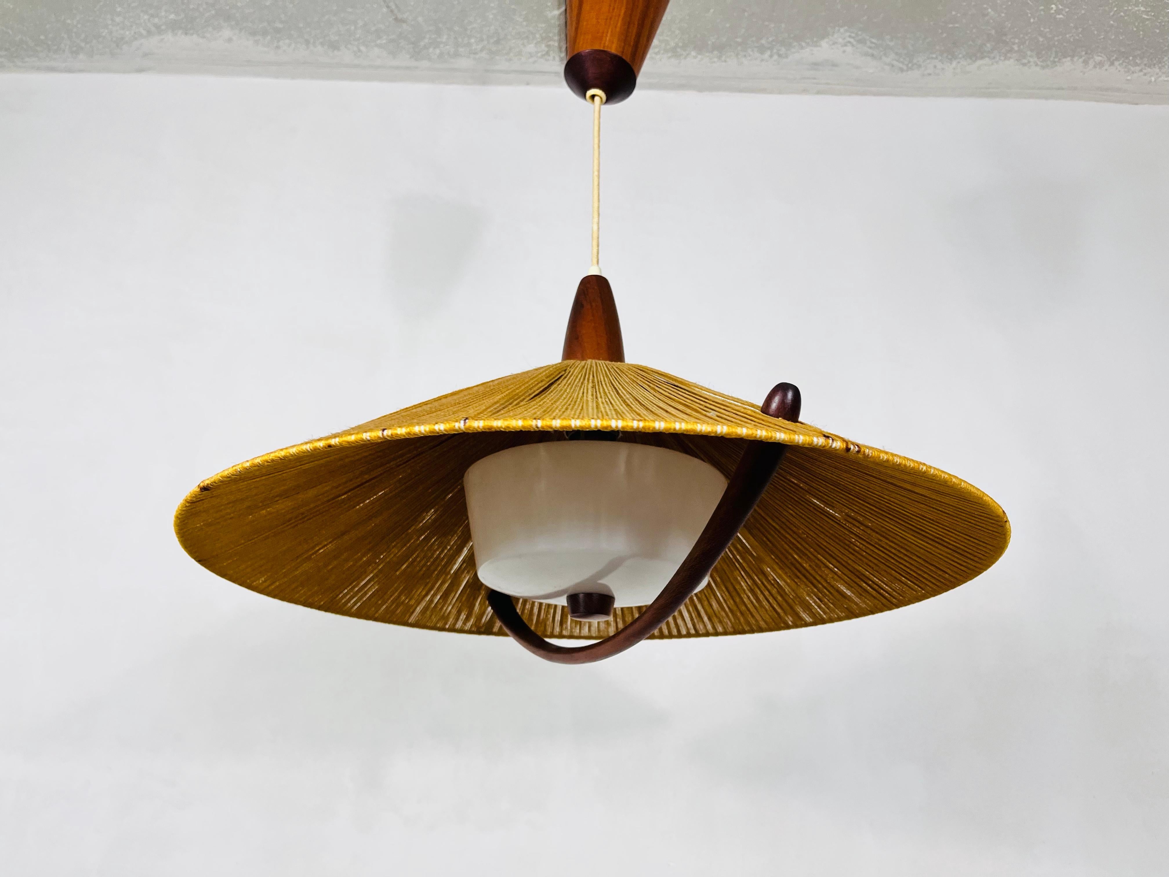A wonderful teak hanging lamp made in the 1960s by Temde in Switzerland. It is fascinating with its rare lamp shade, which gives the lighting a wonderful japanese design.

The height is adjustable from 30 cm up to 110 cm.

The light requires one E27