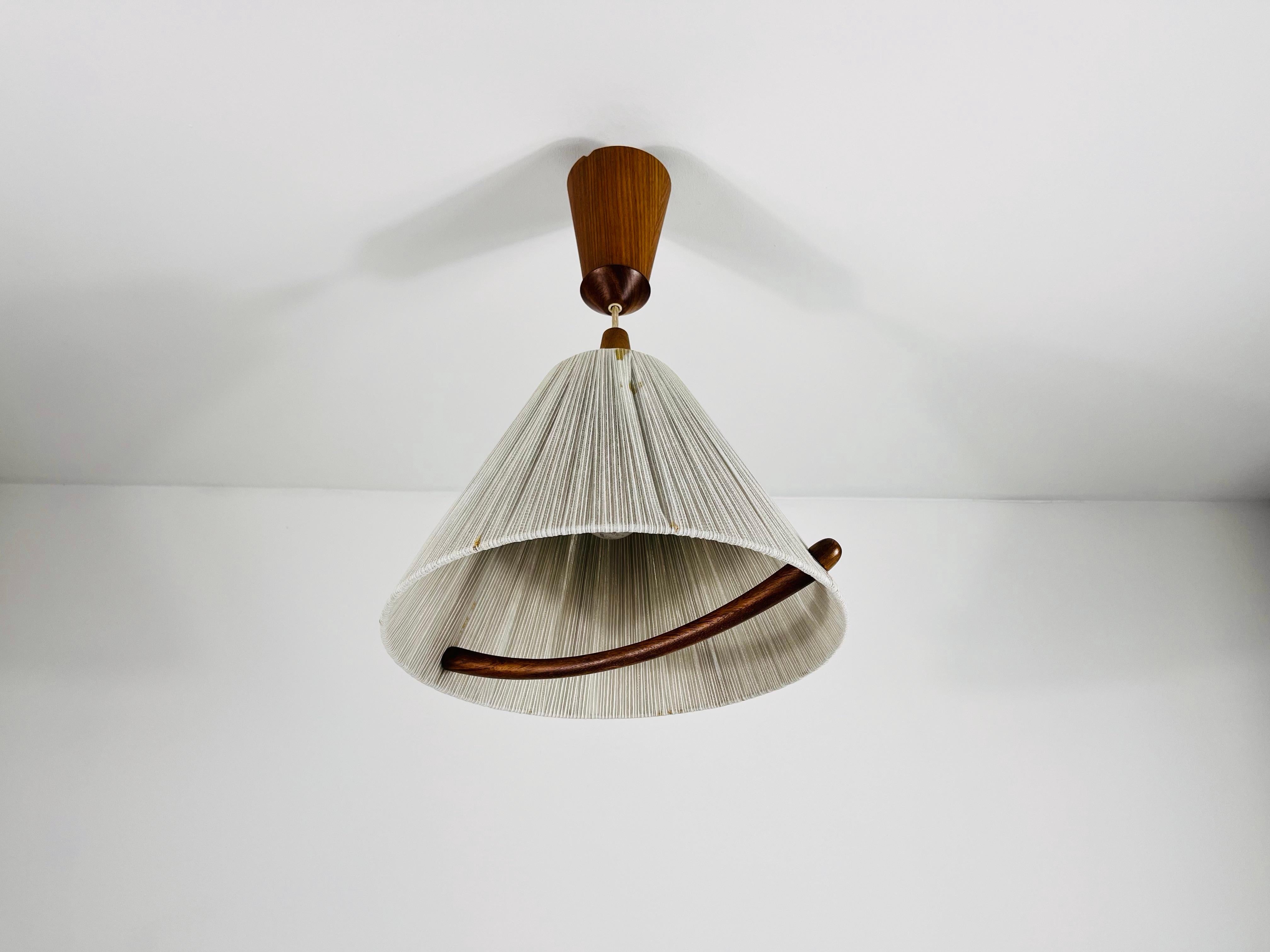 Una lampada a sospensione in teak degli anni '60, realizzata dall'azienda svizzera Temde. Questo pezzo, curato nei minimi dettagli, è un esempio di perfezionismo e qualità, con un design di ispirazione giapponese. Realizzato con materiali naturali e