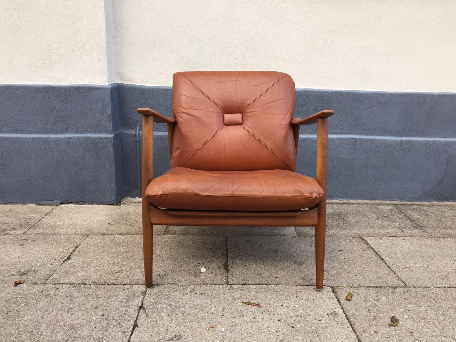 Danish lounge chair/easy chair with teak frame and oak armrests. Its removable cushions are upholstered in brown leather with square jumbo-buttons. It was manufactured by a Danish furniture maker during the early 1960s. The style of this chair is