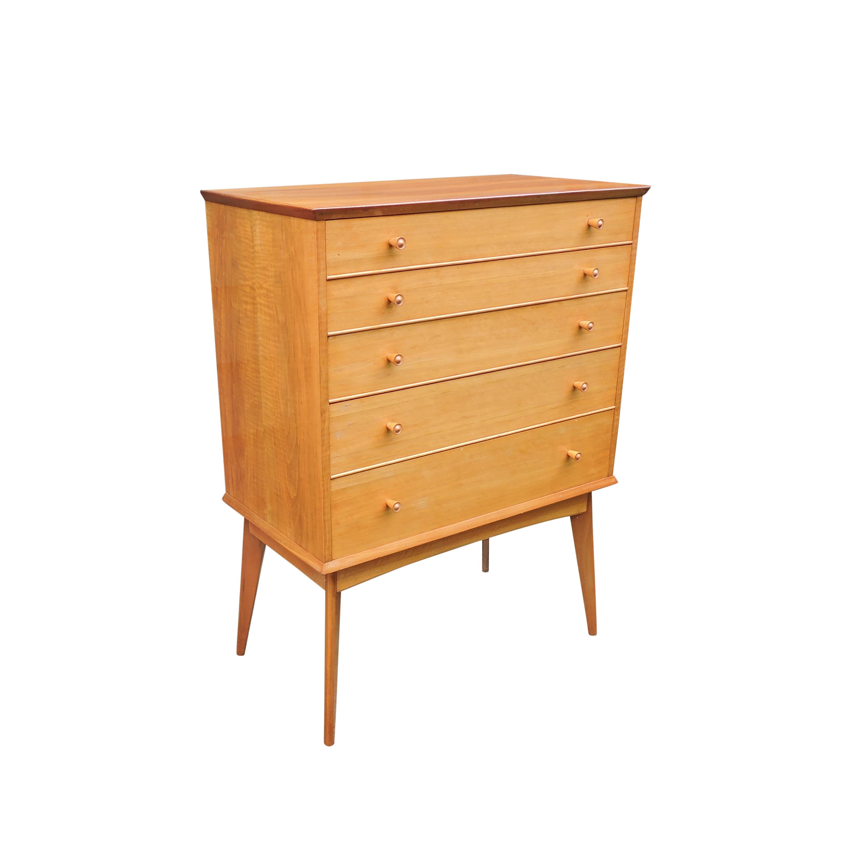 This 1950s teak and walnut chest of drawers was designed and manufactured by cabinet maker Alfred Cox, Great Britain.