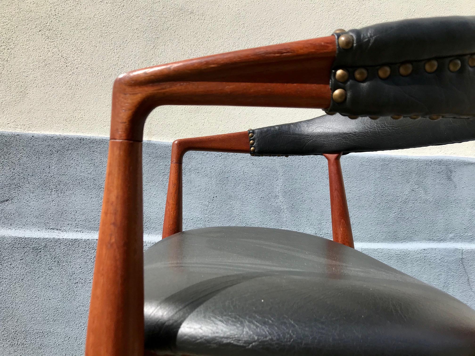 Teak armchair in black faux leather upholstery. 'Goth' Finnish with patinated brass dots. It was designed by Kai Kristiansen in 1959 and made by Eilersen as a commission piece for IKEA in Denmark.