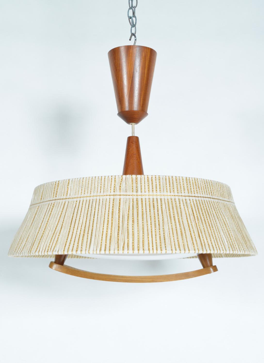 Un luminaire très élégant et utile, particulièrement adapté au dessus d'une table de salle à manger, par la société germano-suisse The Table Company Leuchten. u2028La poignée en teck permet à l'utilisateur de régler facilement la hauteur. Le câble