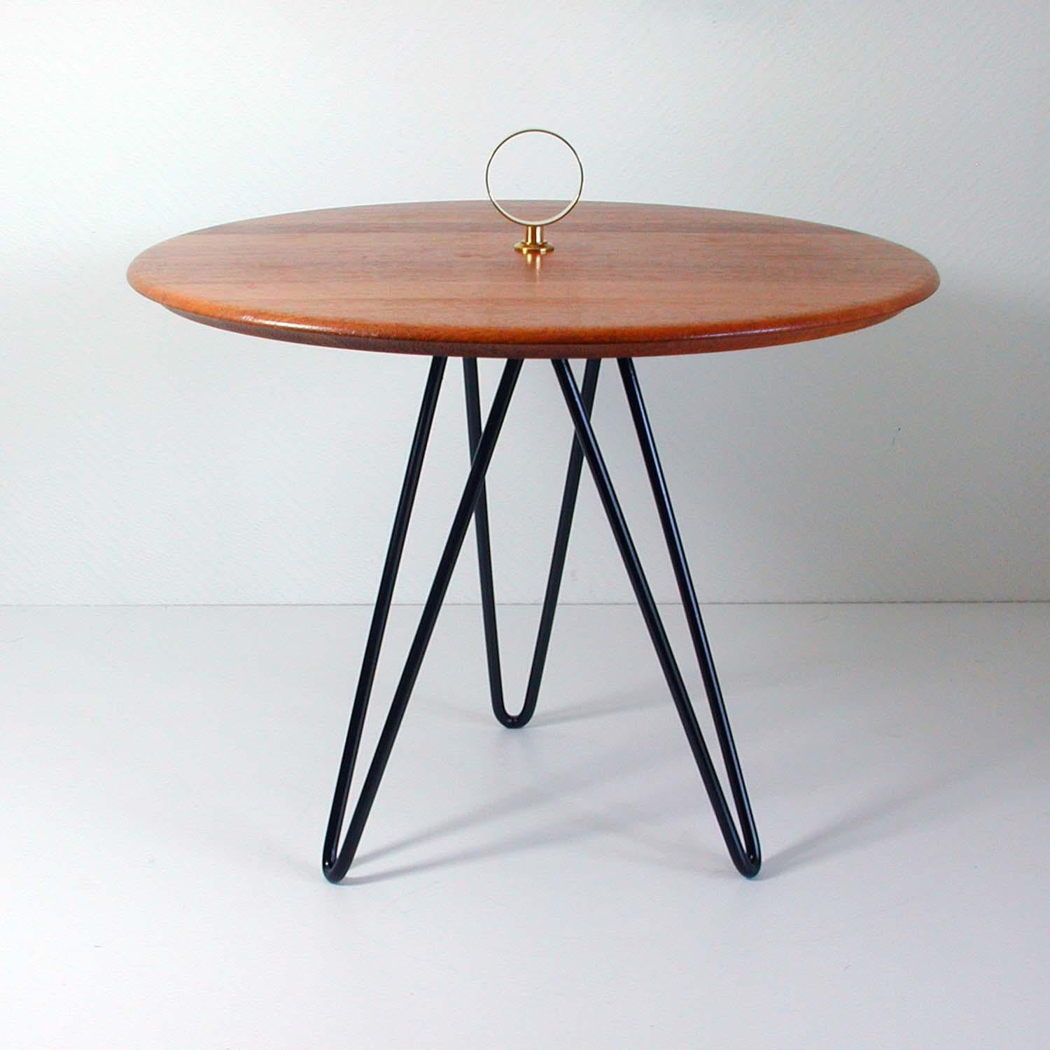 This round vintage tripod side table was made in Denmark in the 1950s to 1960s by Digsmed. It has a black lacquered cast iron string style base, a teak table top and brass details.