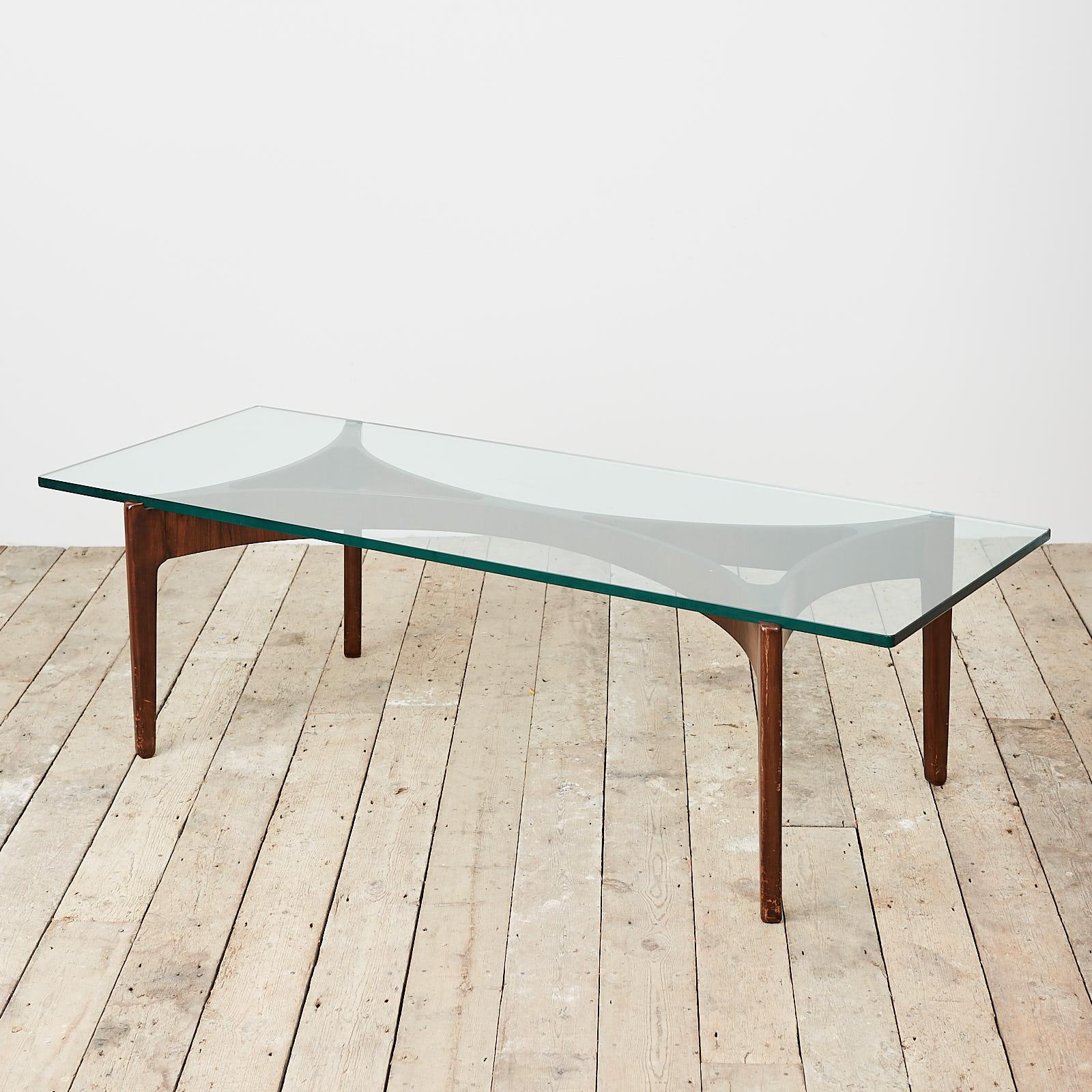 A cocktail table by Sven Ellekaer, with a curved teak base and glass top. Manufactured by Christian Linnebergs Møbelfabrik, Denmark, circa 1960. There are some losses to the teak base and a small chip to the top.
