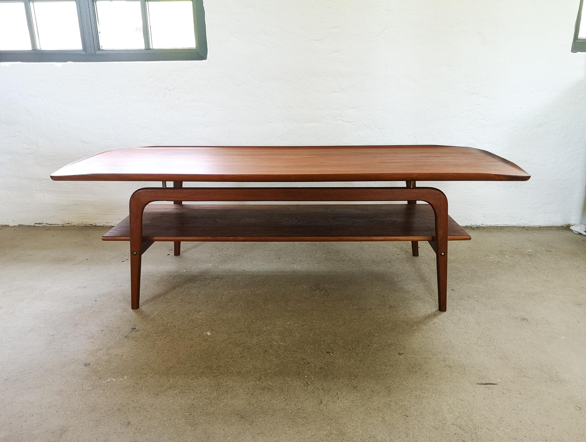 Danish teak table designed by Arne Hovmand-Olsen for Toften Mobelfabrikken, early 1960s, Denmark. 

With it turned-up ends and a ‘floating’ top thanks to its brass
spacers add to its overall sleek, gives this table a top-quality feel. There is