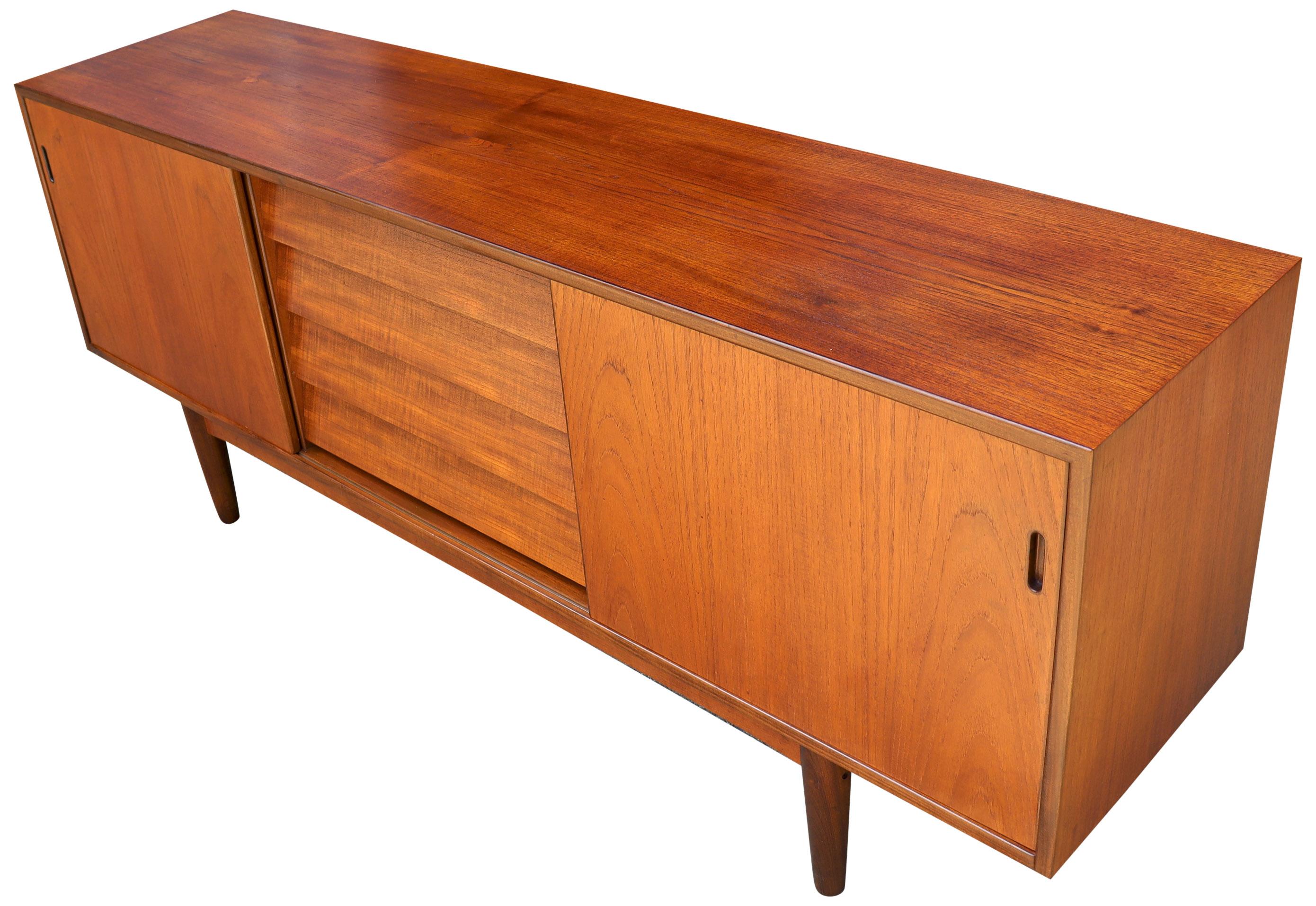 Beautiful Danish modern teak wood credenza or console featuring center louvered drawers and shelves hidden by sliding doors on either side. Exceptional finished back allows placement anywhere in your space. Each cabinet section is 24'' width.