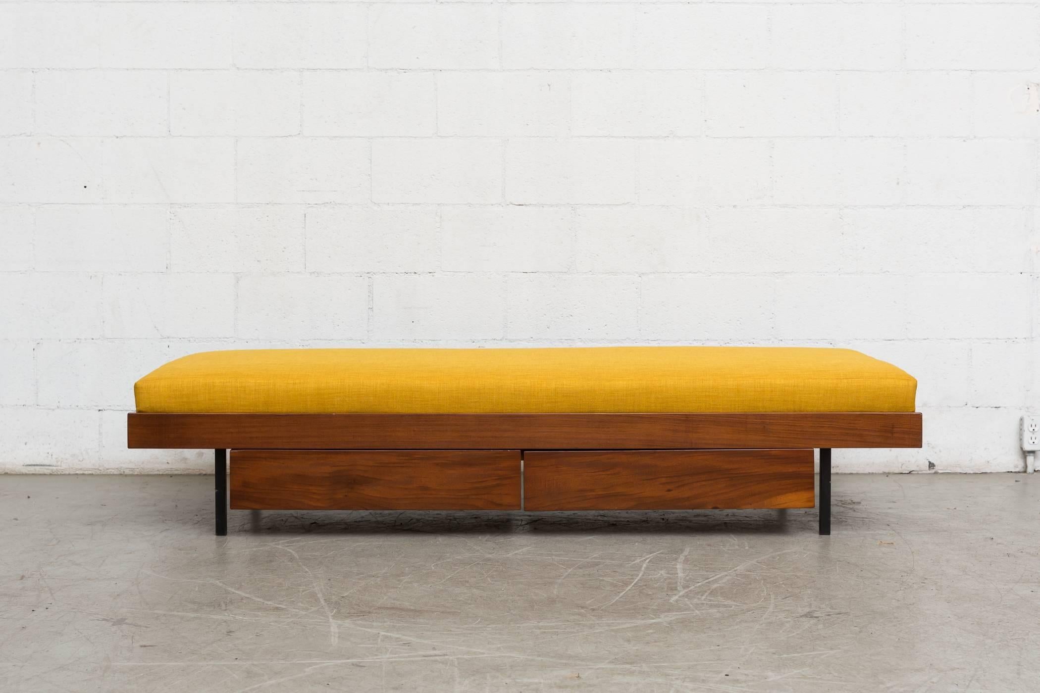 Lightly refinished midcentury teak daybed with double lower storage drawers and black enameled metal legs. New mustard yellow upholstered mattress. In good original condition.
