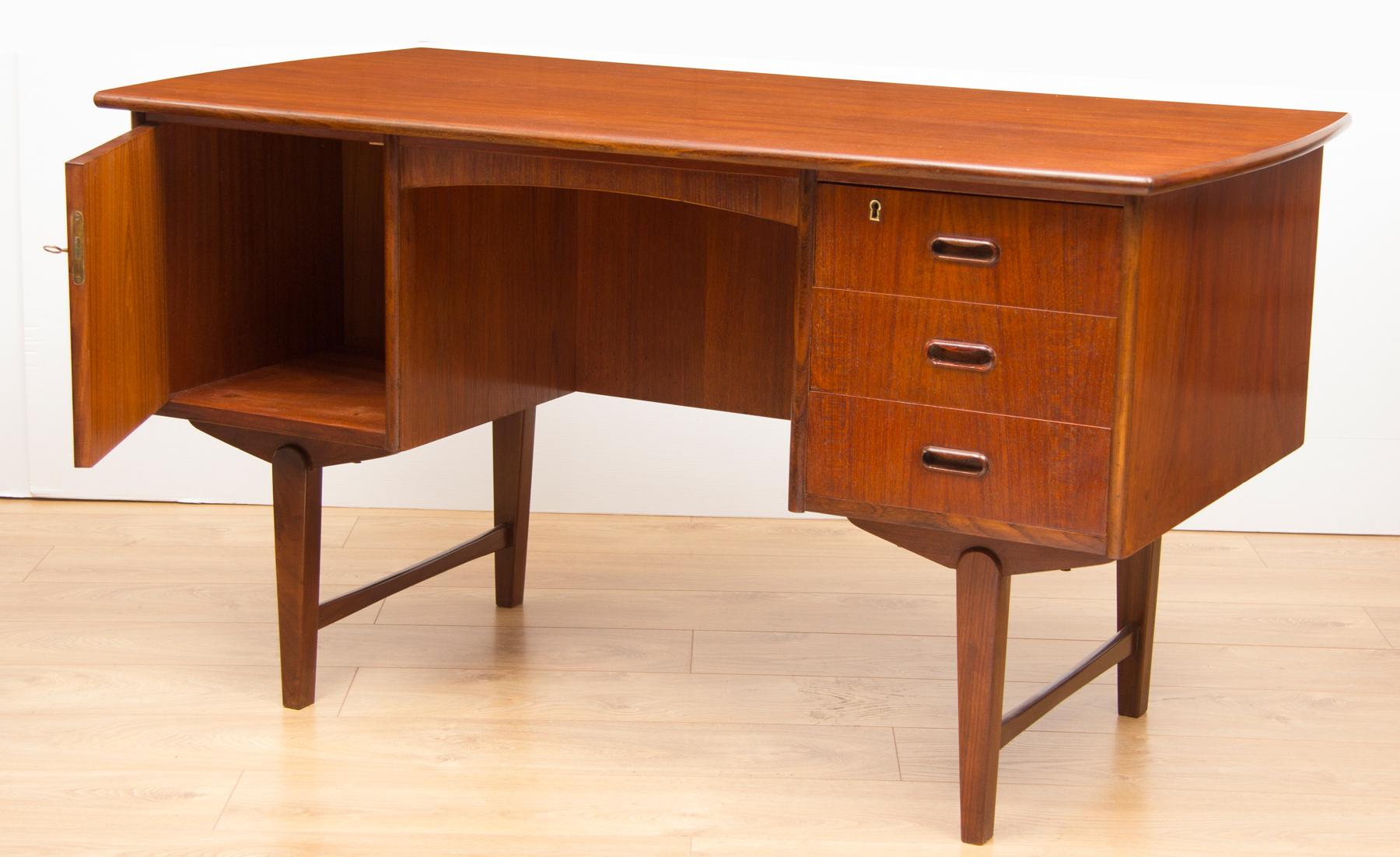 Midcentury teak desk, circa 1960.Featuring drawers and a door to the front and a bookshelf and drop down cabinet to the rear.
