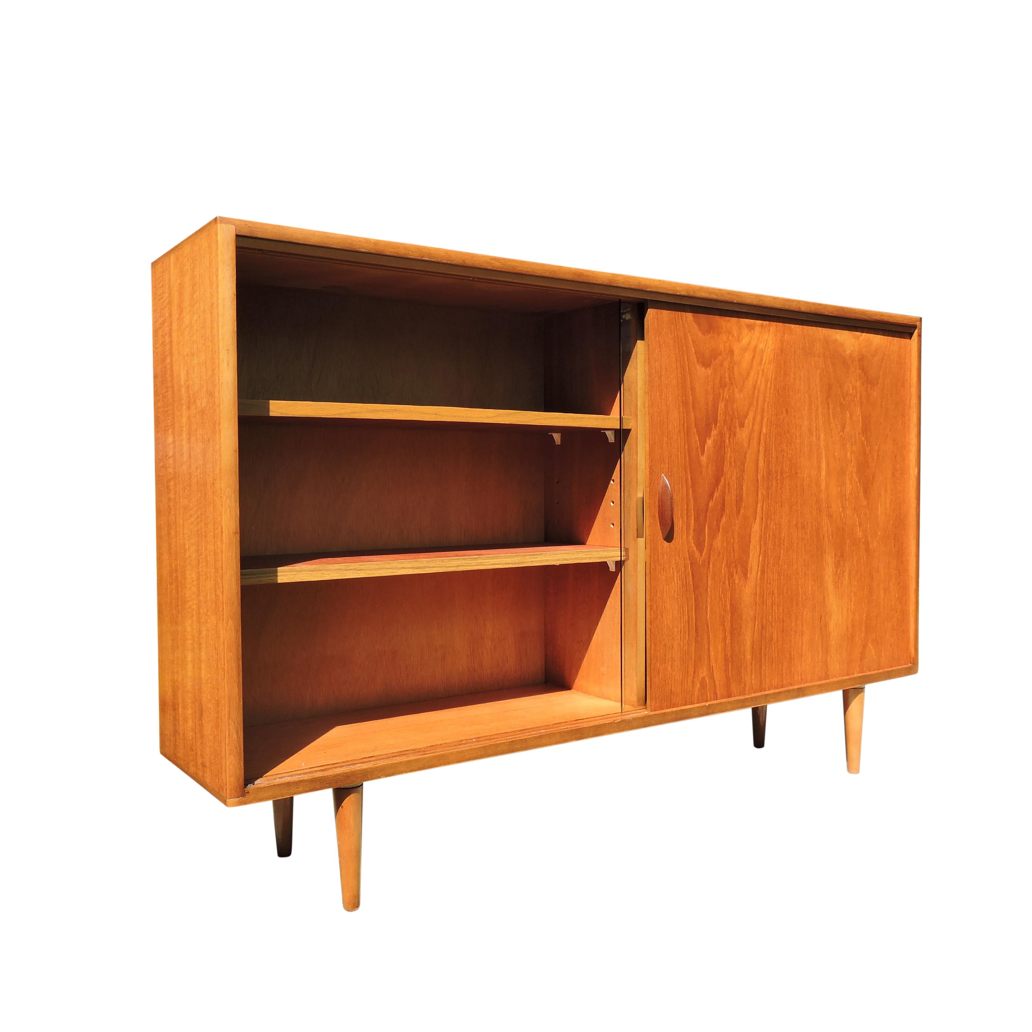 - Display cabinet with teak shelves
- Remains in solid and sturdy condition
- Features one glass sliding door and one teak sliding door
- Stands on tapered feet.