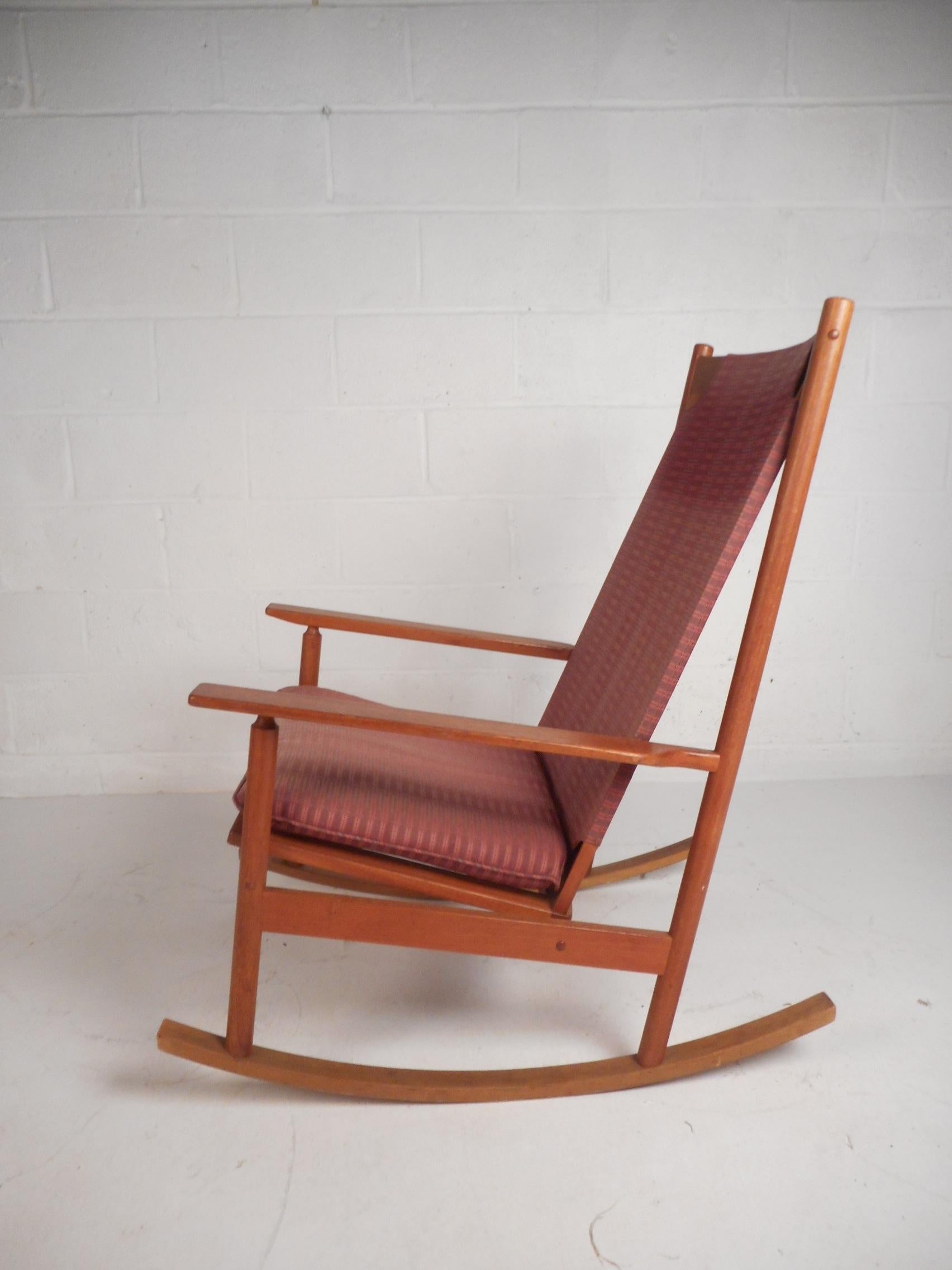 This beautiful vintage modern rocking chair features a sculpted teak frame and a thick seat cushion. The spring seat supports under the cushion allow for maximum comfort during long periods. A stylish chair with an angled back rest and low arm rests
