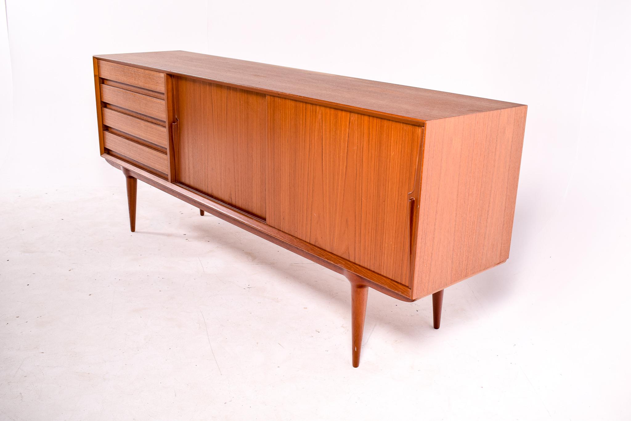 Designed by Gunni Omann in the 1960s, this sideboard conjugates the simplicity of the running doors with the drawers and the attractiveness of a beautiful veneer. The detail of the legs rounding size to receive perfectly the sideboard is also very