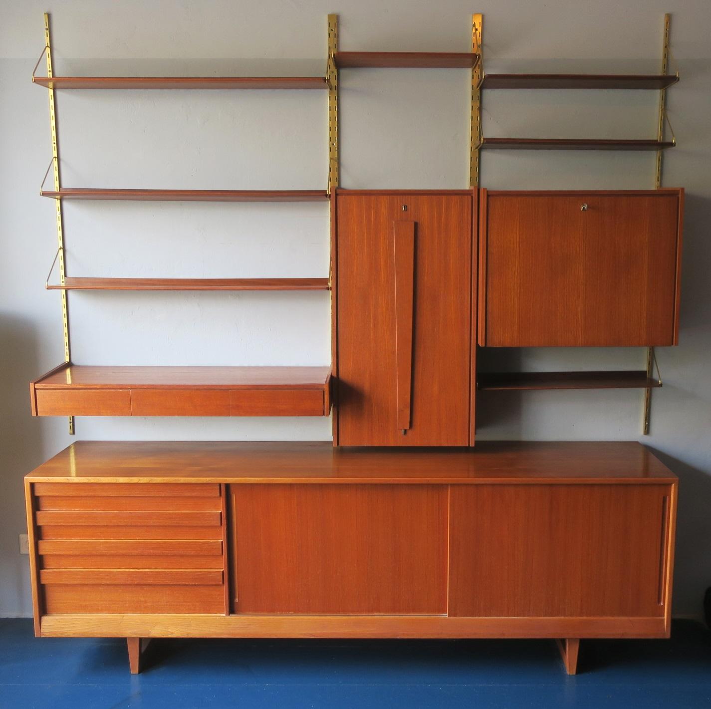 Midcentury teak modular wall shelf system with a matching low sideboard; drop-down desk revealing an ebonized and mirrored interior with small shelves when opened, with its original green-papered back; a set of 3 hanging drawers; mirrored cupboard