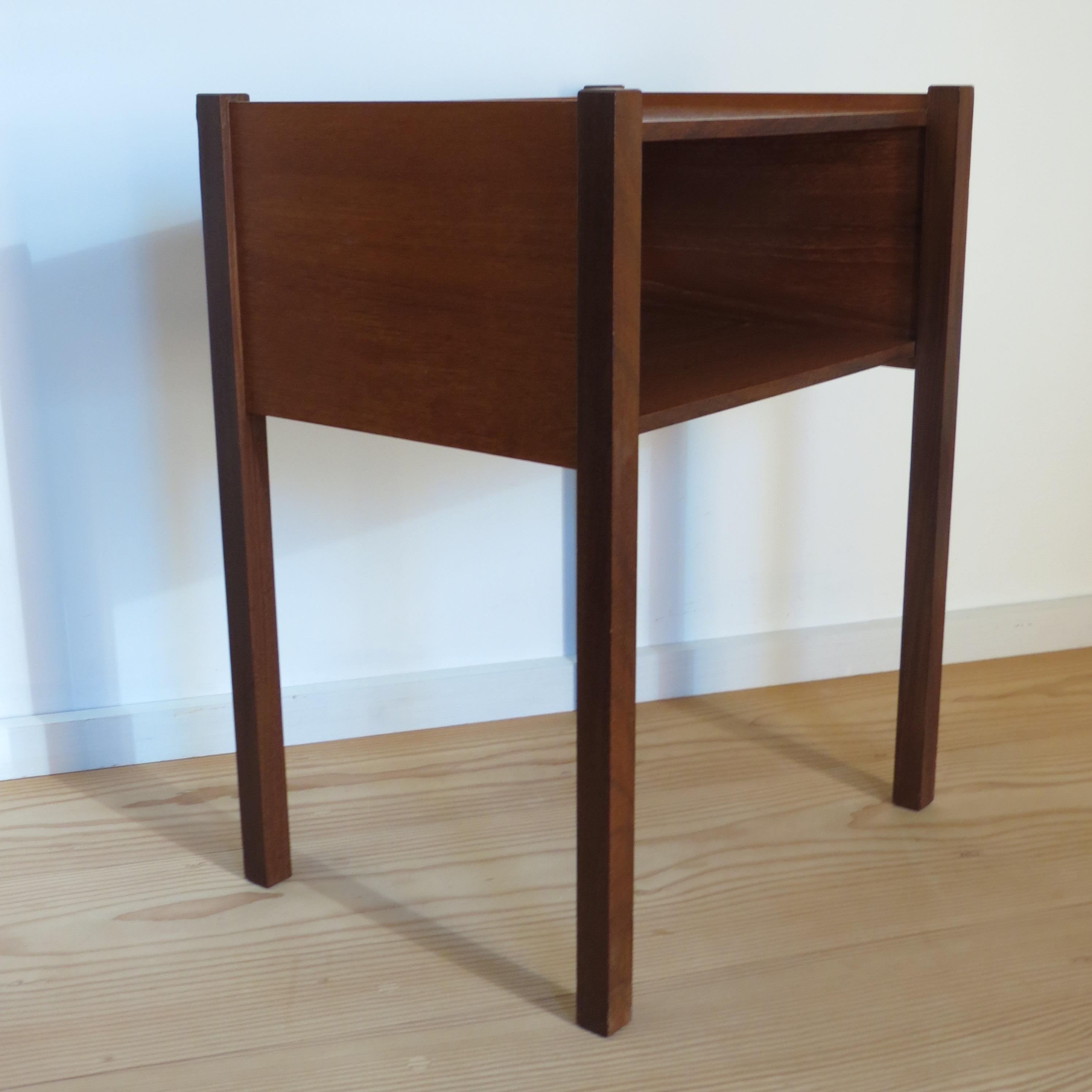 Wonderful night stand bedside table from the 1960s.

Made from solid Afrormosia legs, with Teak top and shelf.   Very good quality, elemental design.

Good vintage condition.

Shelf gap measures 16.5cm tall 41.5cm wide

ST1516.