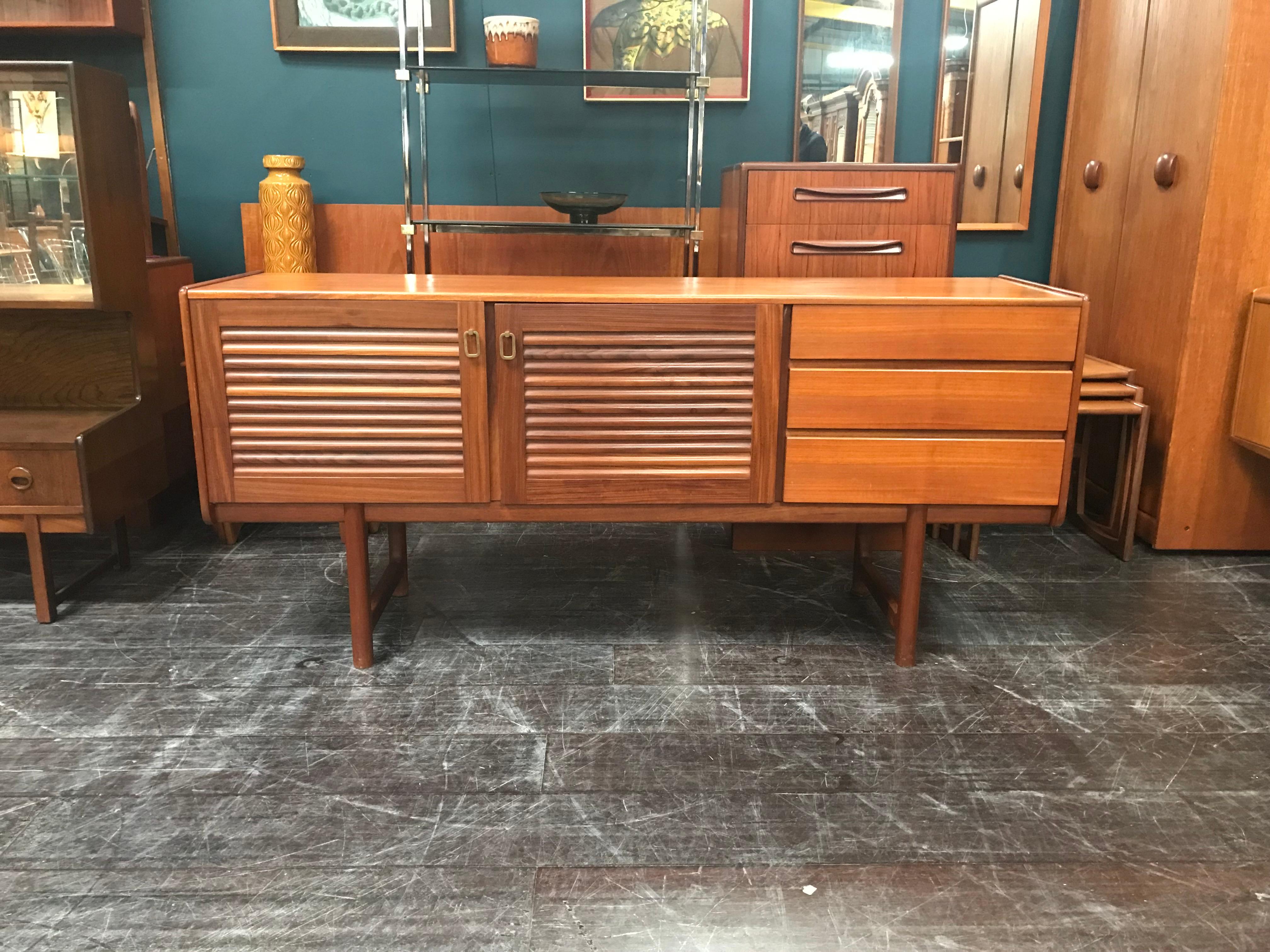 A vintage teak sideboard designed by Tom Robertson and manufactured by A.H. McIntosh of Kirkcaldy. This Classic piece of Scottish midcentury Furniture features extensive storage, with three drawers set to the side of a double cupboard. The sideboard