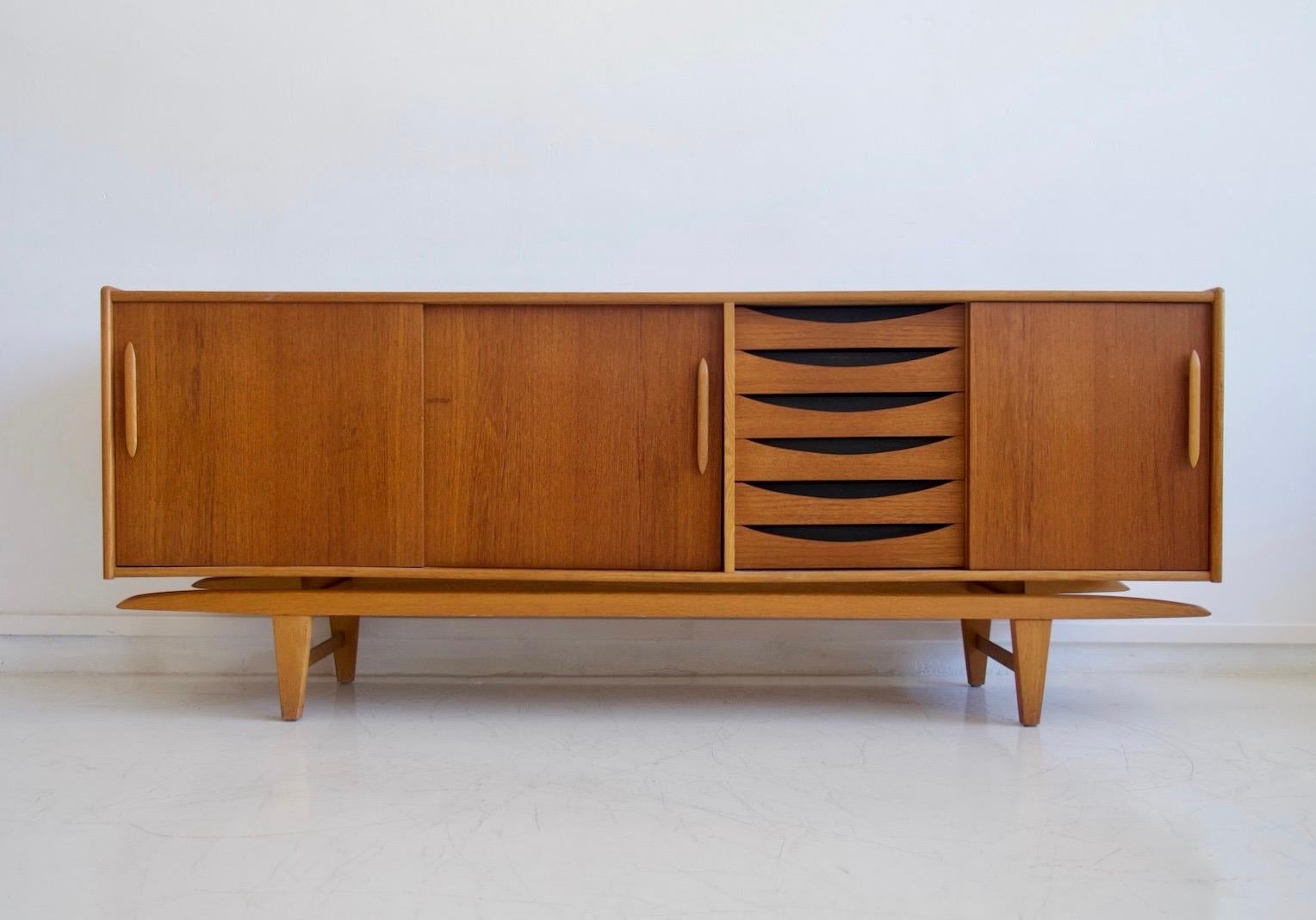 Teak sideboard manufactured in Sweden by Ajfa Tibro, circa 1970. Interior drawers made of oak. Front with sliding doors that reveal shelves on both sides and six drawers. The sideboard is slightly raised from its base, giving it a nice 