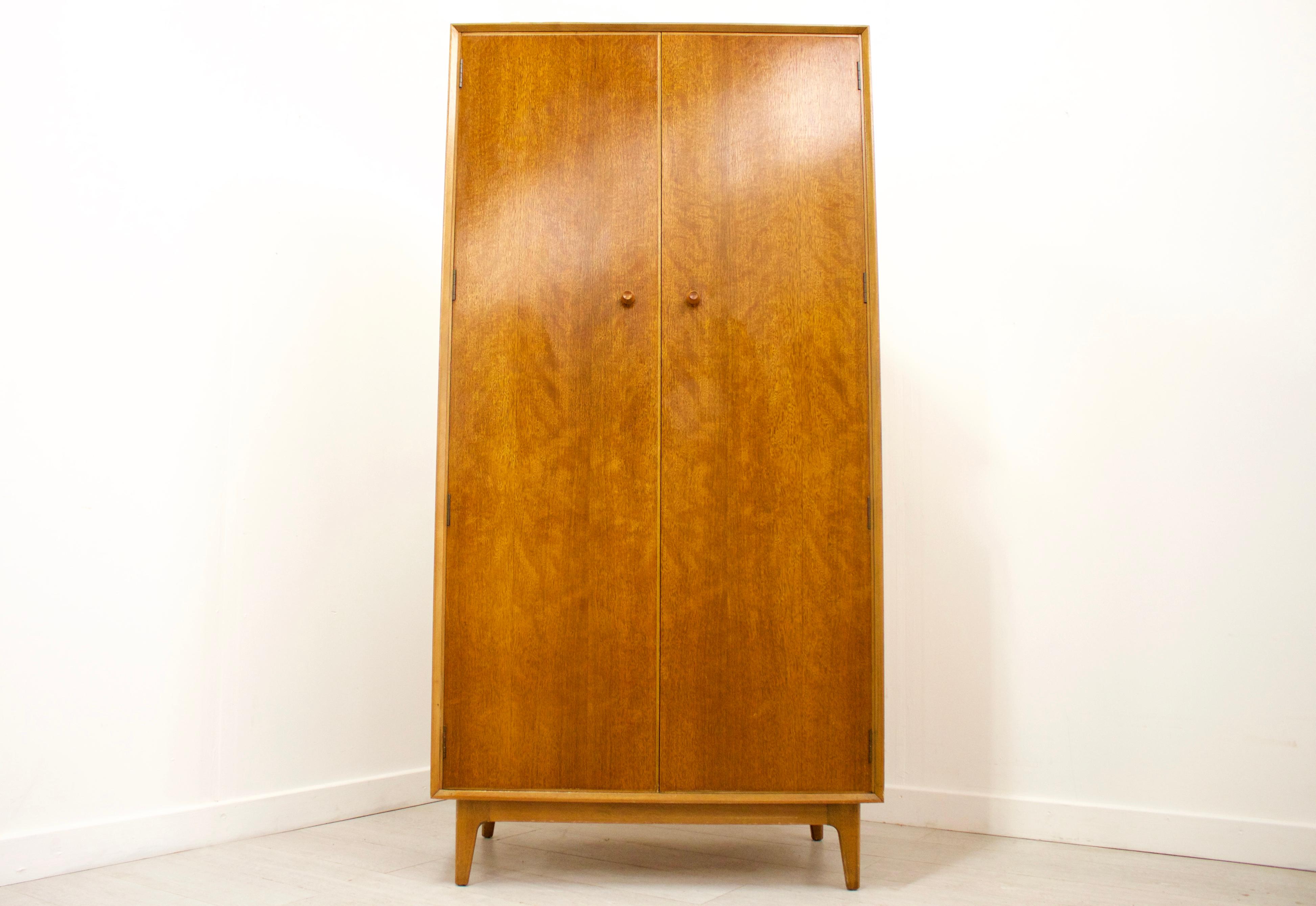 This is a very stylish solid teak and walnut veneer wardrobe by Gimson & Slater for Vesper.

This wardrobe features a hanging rail to the left side, and shelves to the right for ample storage. It also features a tie rack on the inside of the right
