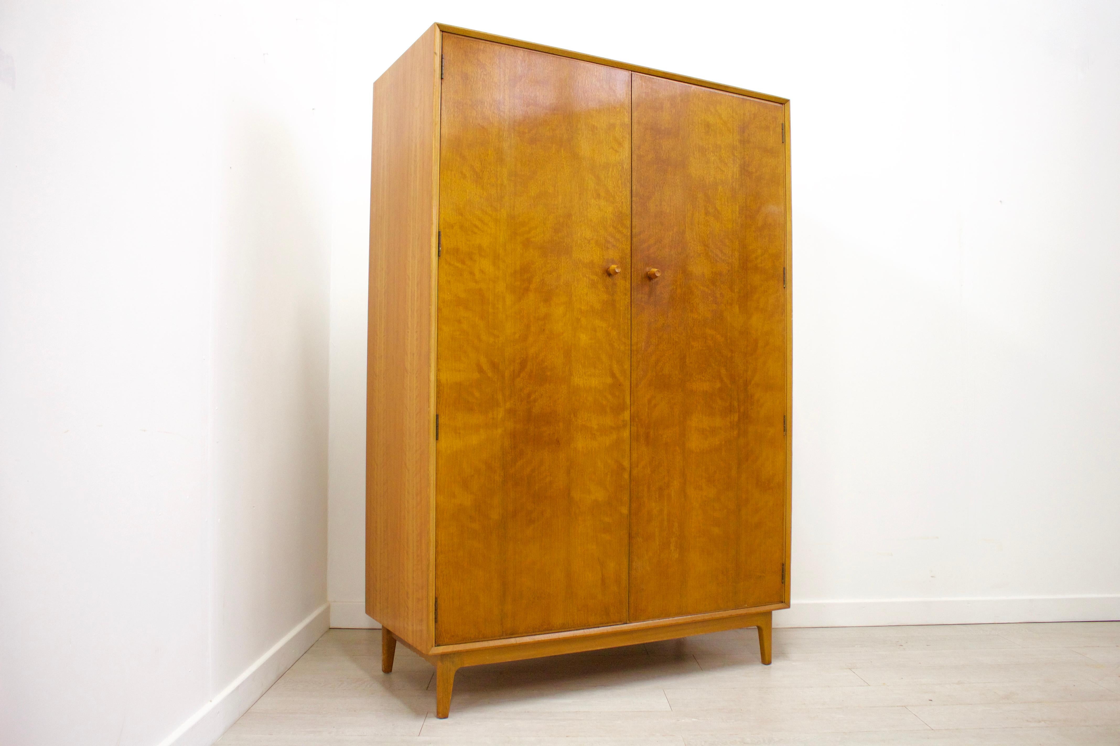 This is a very stylish solid teak and walnut veneer wardrobe by Gimson & Slater for Vesper.

This wardrobe features a hanging rail to the left side, and shelves to the right for ample storage.