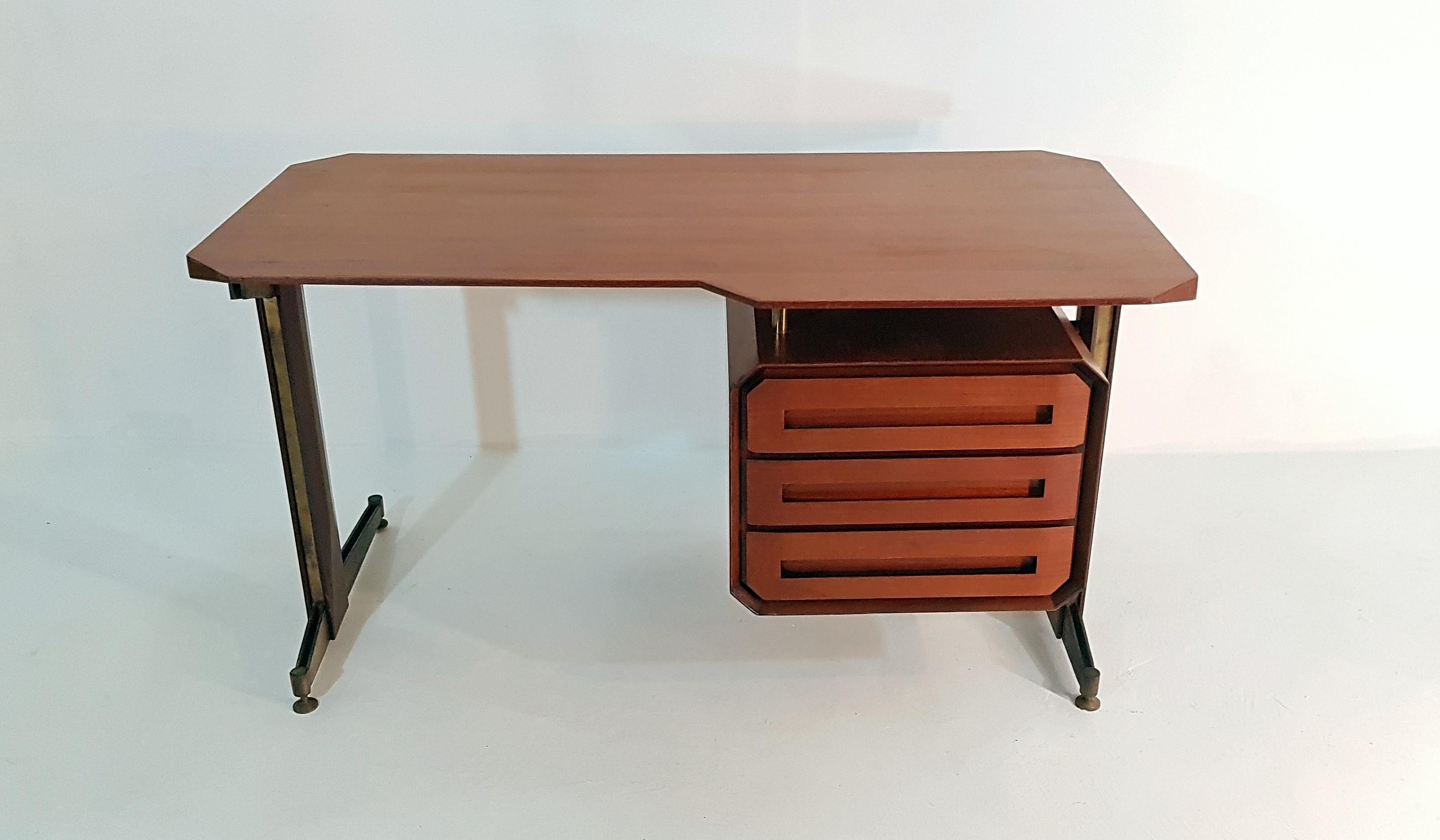 Beautifully designed Italian writing desk in teak and brushed brass. With a very distinct design this desks every wood surface has been given specific angles such as the tabletop, the unit with drawers as well as the side of the legs. The angles as