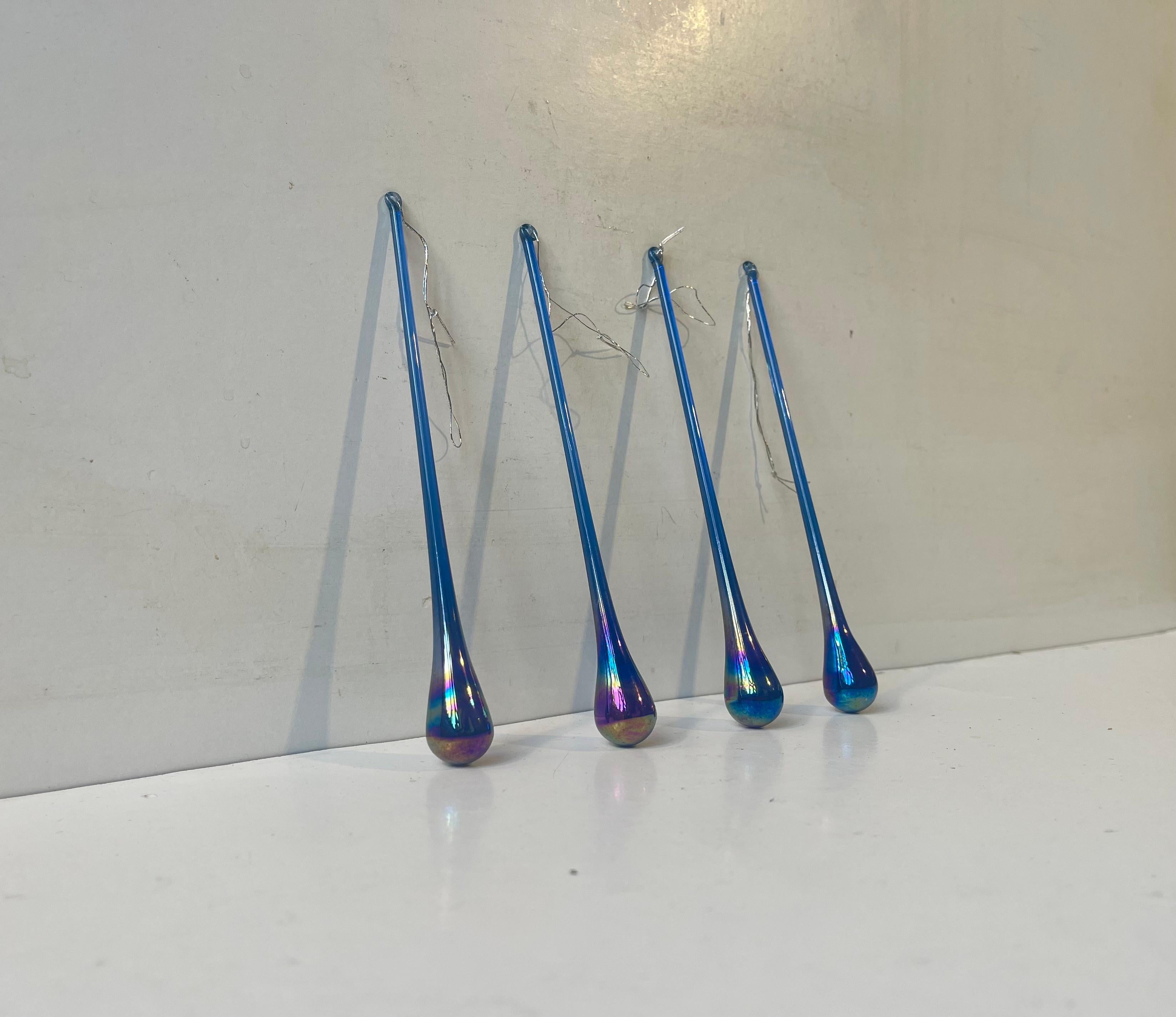 Un ensemble de 4 ornements en verre en forme de goutte d'eau ou d'attrape-soleil en verre bleu cobalt irridescent. Verrier scandinave inconnu vers 1970-80. Dimensions : H : 15 cm (sans le cordon), l/d : 2/2 cm. Le prix est pour le lot de 4.