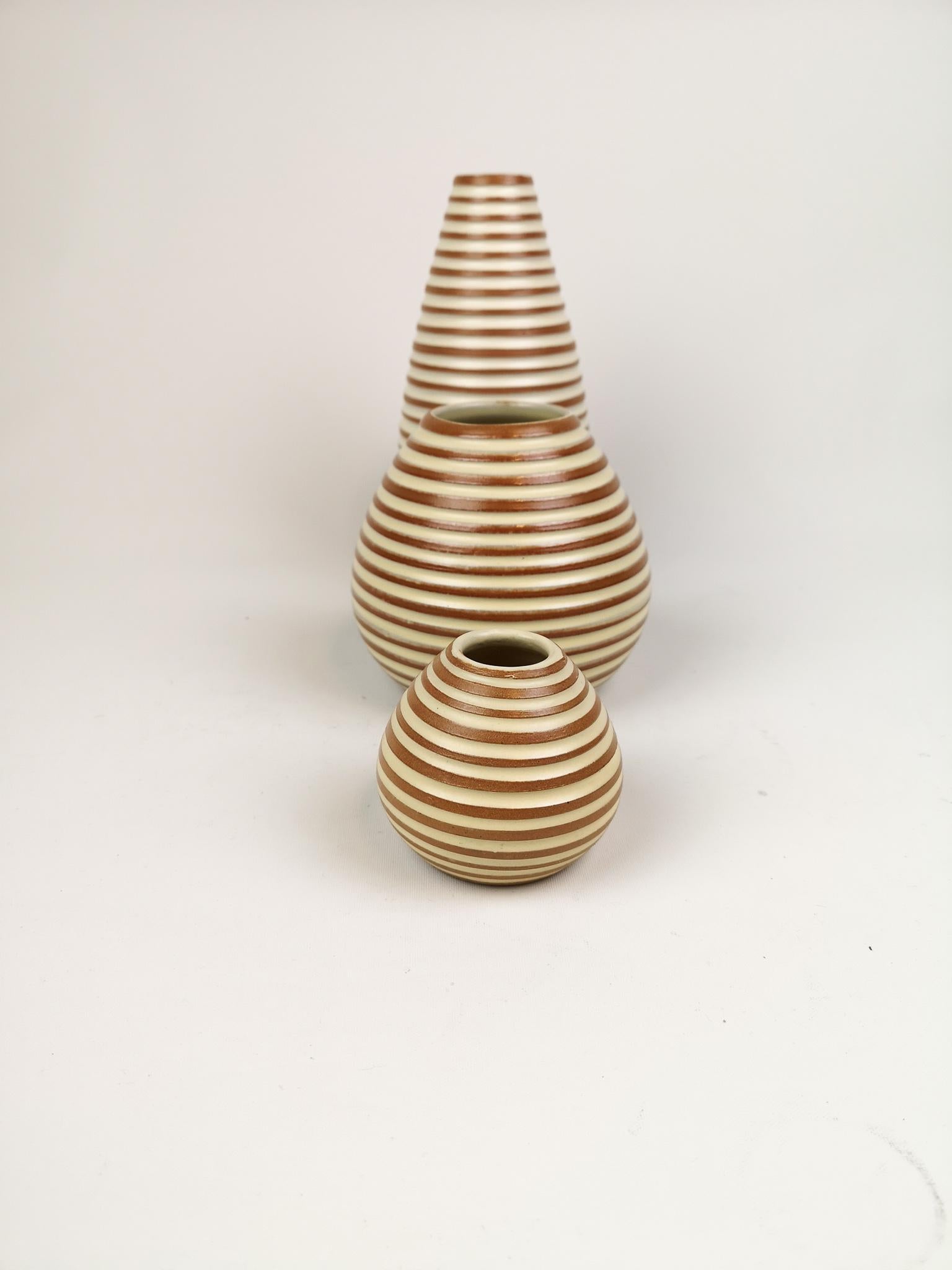 Ingrid Atterberg is the creator of these vases produced in Sweden at Upsala Ekeby in the 1950s. They have a nice art deco look with a terracotta base and white rings around it. 

Good condition.

Measures. The large H 22 cm, D 10cm, middle H 13,