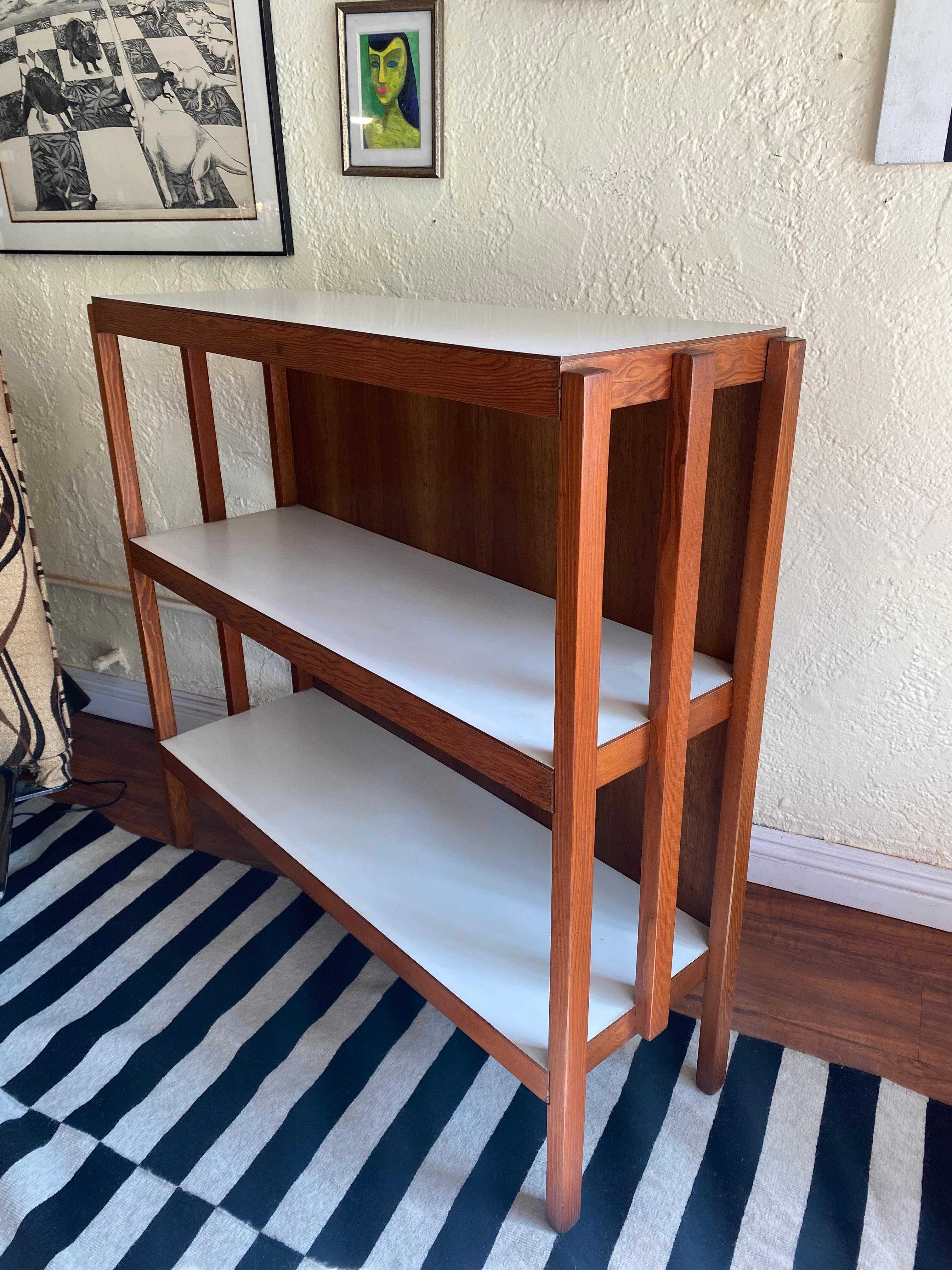 Questa libreria a tre livelli riflette il design moderno del Medioevo grazie alle sue linee pulite e all'uso equilibrato dei materiali. Realizzato in pino e noce, ogni scaffale presenta un piano laminato bianco che crea un sottile contrasto con le