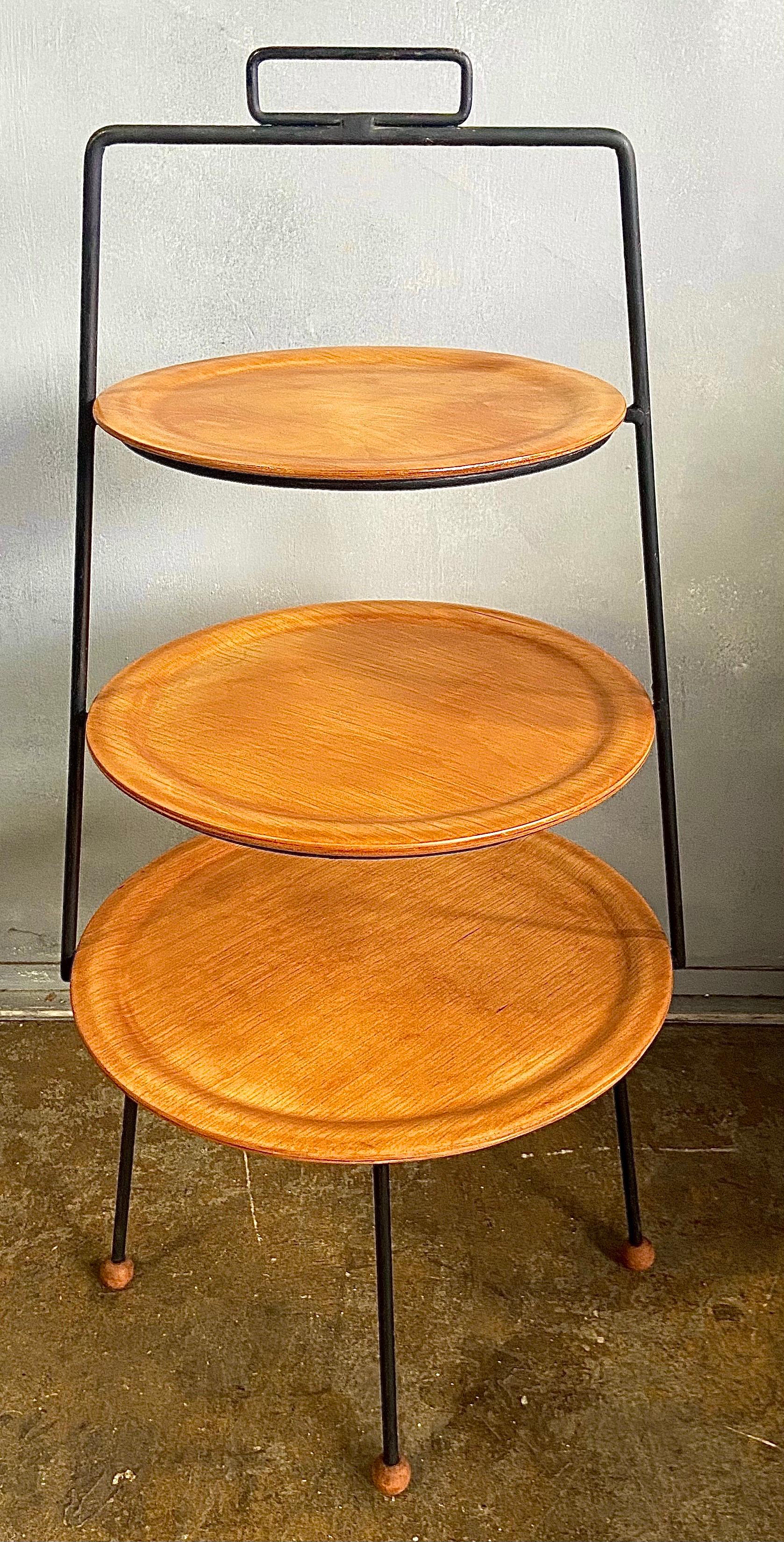 For your consideration is one rare vintage three tiered stand designed by Tony Paul for Woodlin-Hall of NYC, circa 1950s. Featuring bent plywood plates on a black iron frame with wood ball feet. This stand is very versatile and can be used as a