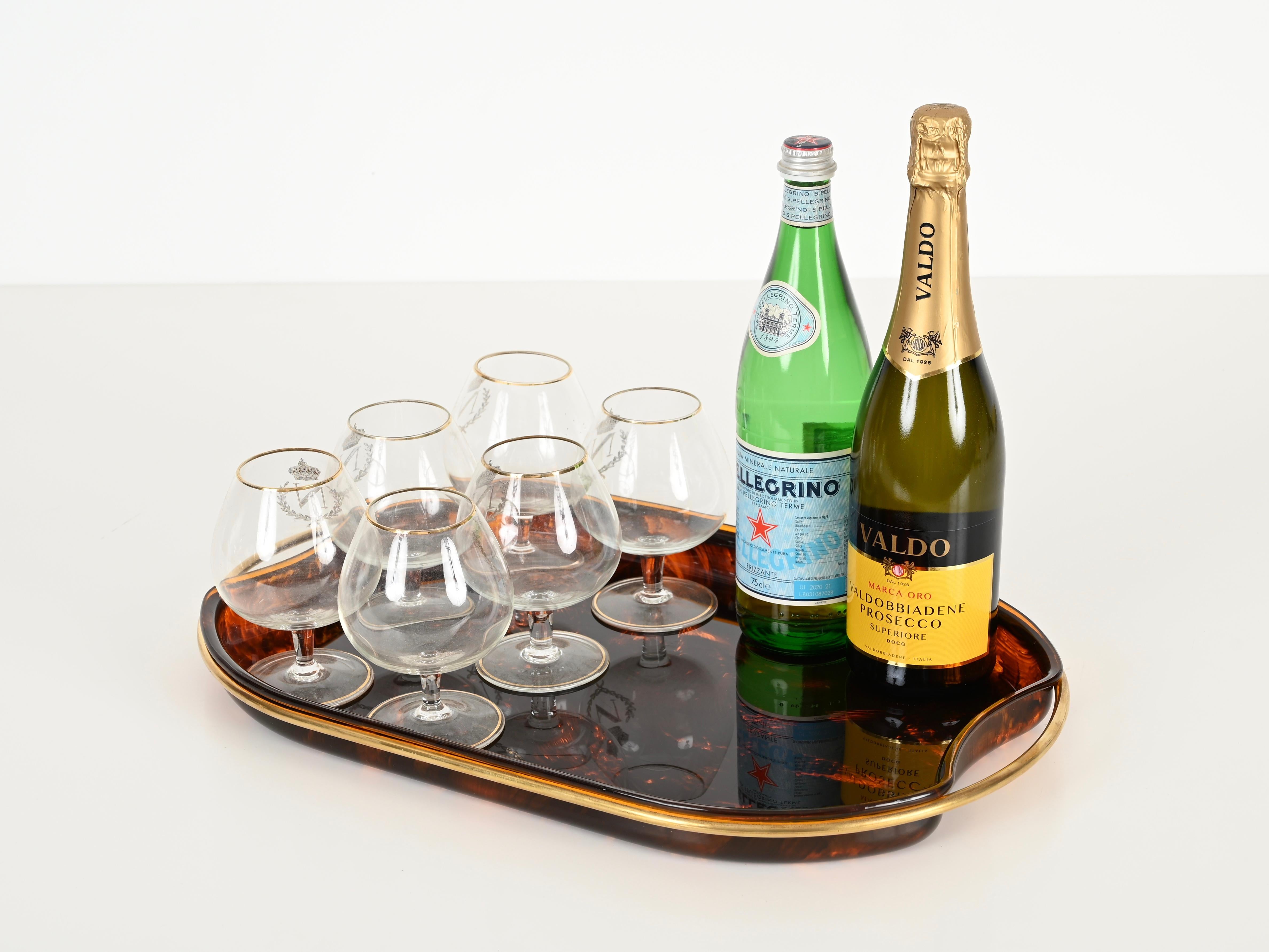Splendido vassoio di metà secolo in lucite effetto tartaruga con maniglie in ottone.  Questo pezzo incredibilmente affascinante è stato progettato in Italia negli anni '70 da Guzzini.

Questo vassoio da portata unico è fantastico grazie ai suoi