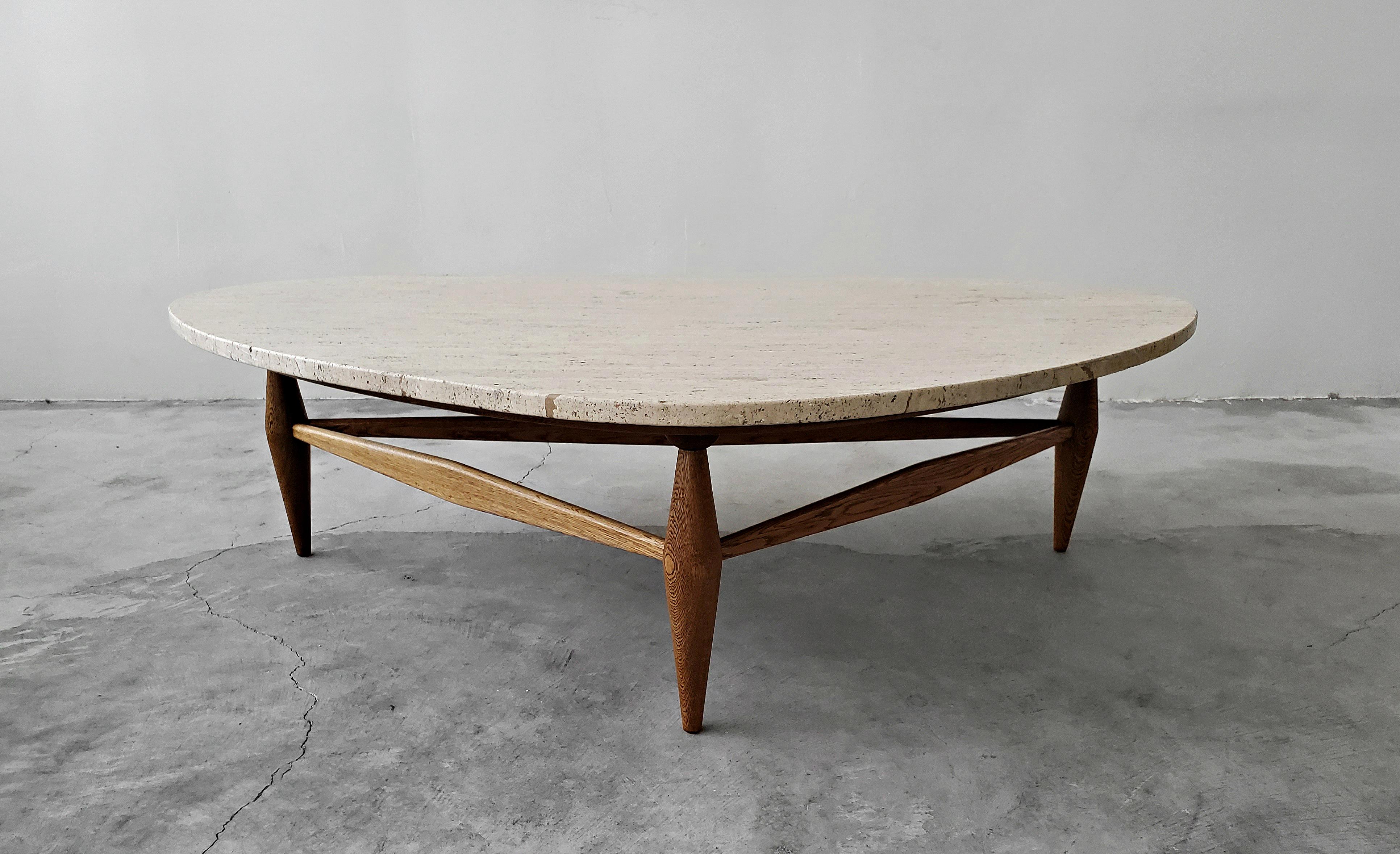 A rare and beautiful combination of travertine and oak. This stunning midcentury coffee table is constructed of a triangular travertine top set on an expertly crafted, sculptural oak base. The base has a large plywood surface that supports the