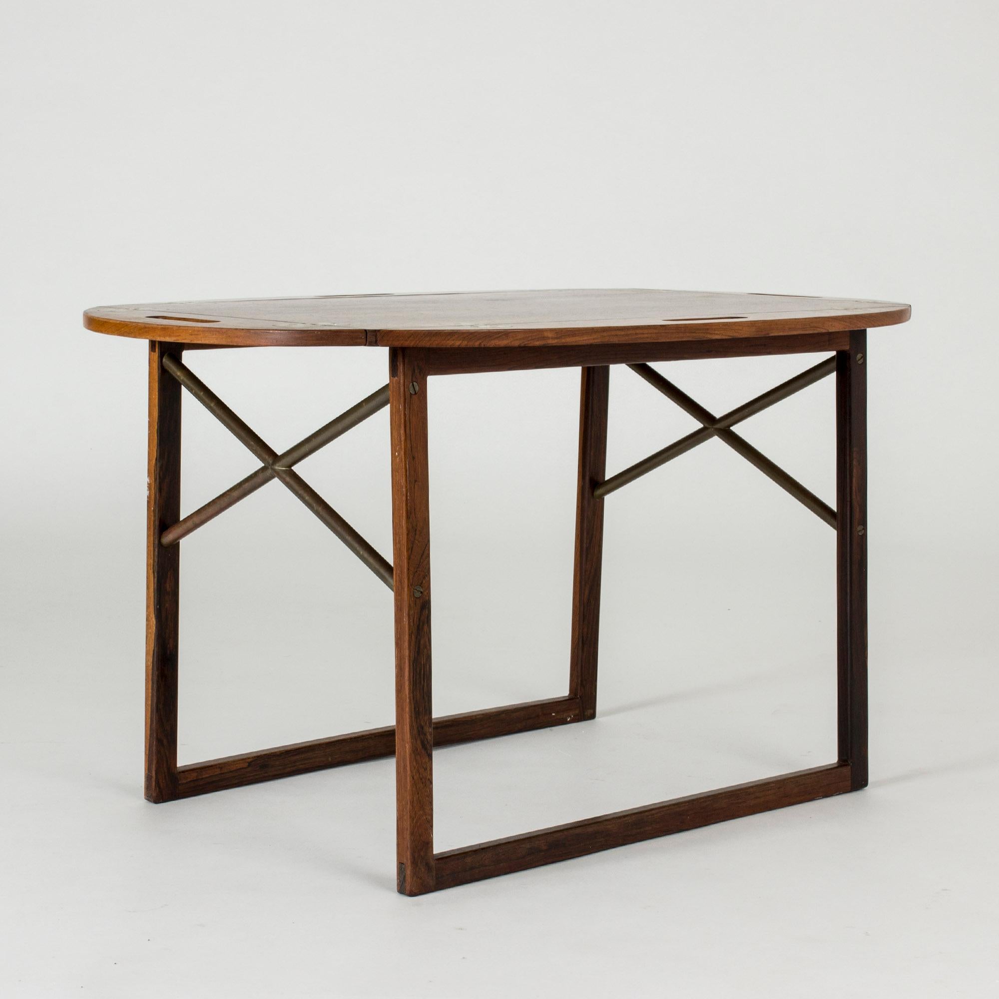 Élégante table basse en bois de rose de Svend Langkilde, dont le plateau peut être soulevé pour servir de plateau. Quatre poignées et la possibilité de relever les bords de la table. La base soignée en forme de traîneau avec des détails en forme de