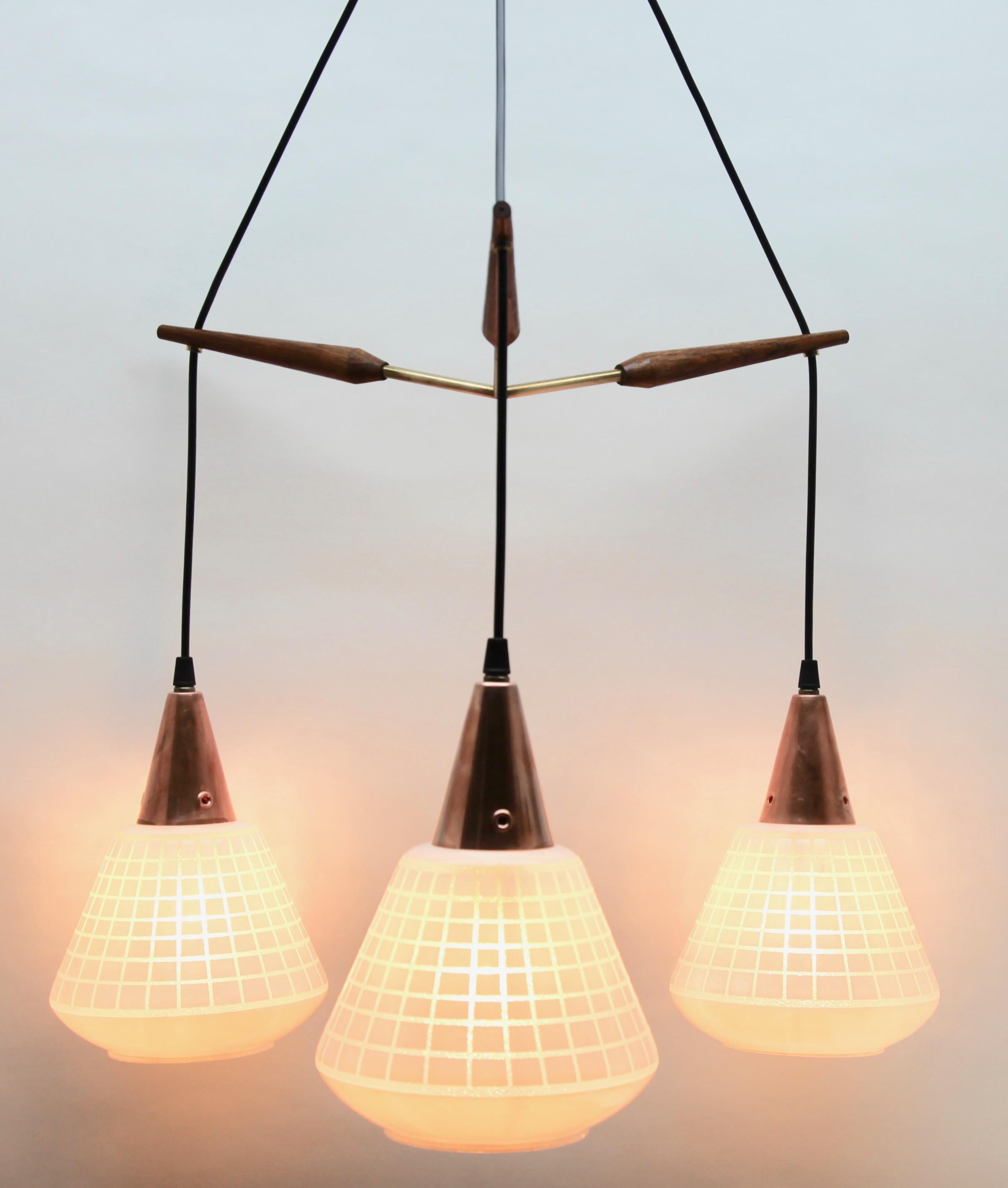 Hanging pendant lights from the late 1950s on an adjustable cable, designed in the Scandinavian style with teak wood and a frosted, light-shade with grid pattern motief
Its Classic modernist form and simplicity in design, making it an iconic example