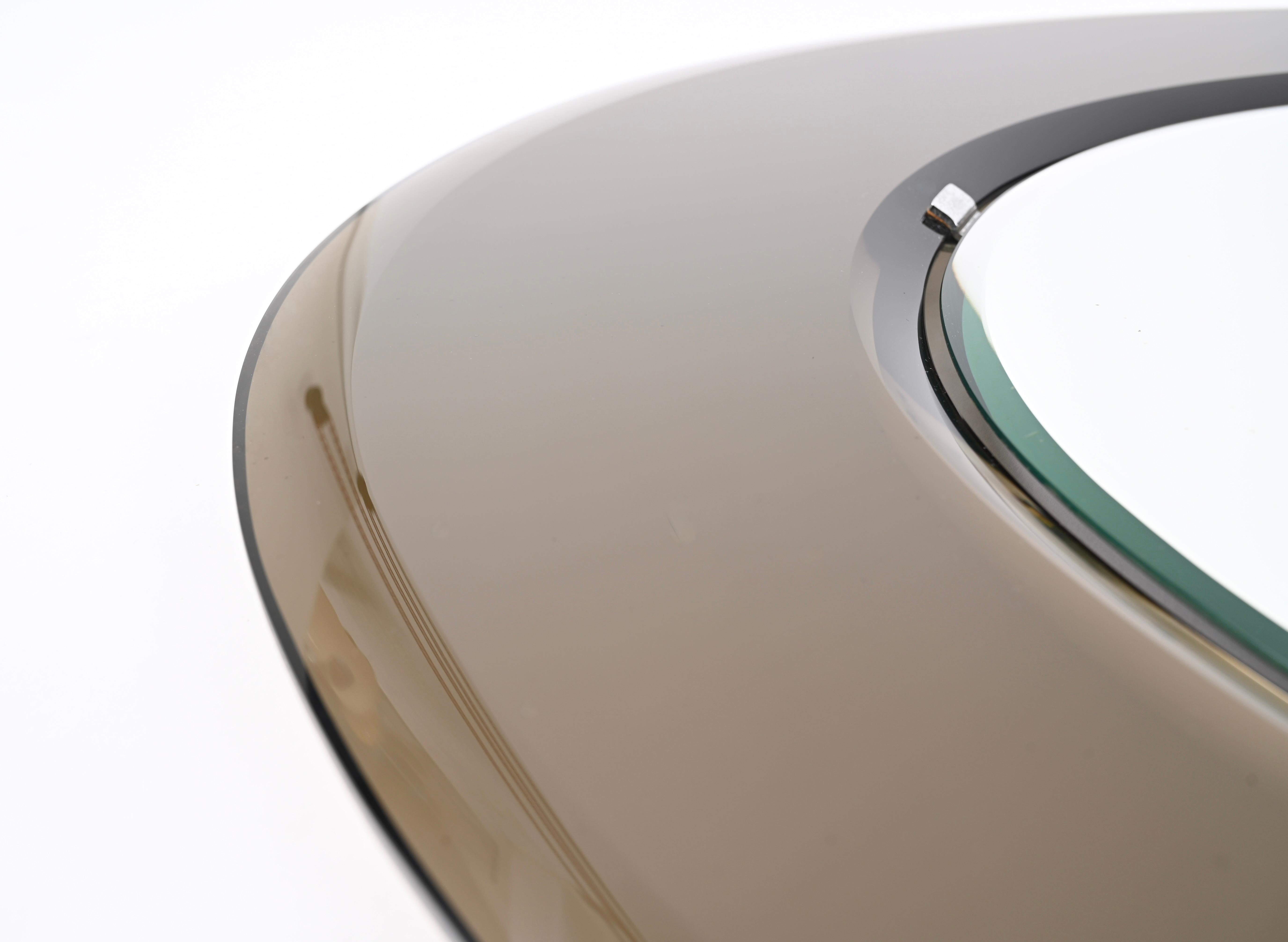 Prächtiger großer, dreifach abgeschrägter ovaler Spiegel aus der Jahrhundertmitte mit einem Spiegelrahmen aus bronziertem Glas. Dieser außergewöhnliche Spiegel wurde in den 1970er Jahren in Italien von Cristal Art hergestellt.  

Der Spiegel hat