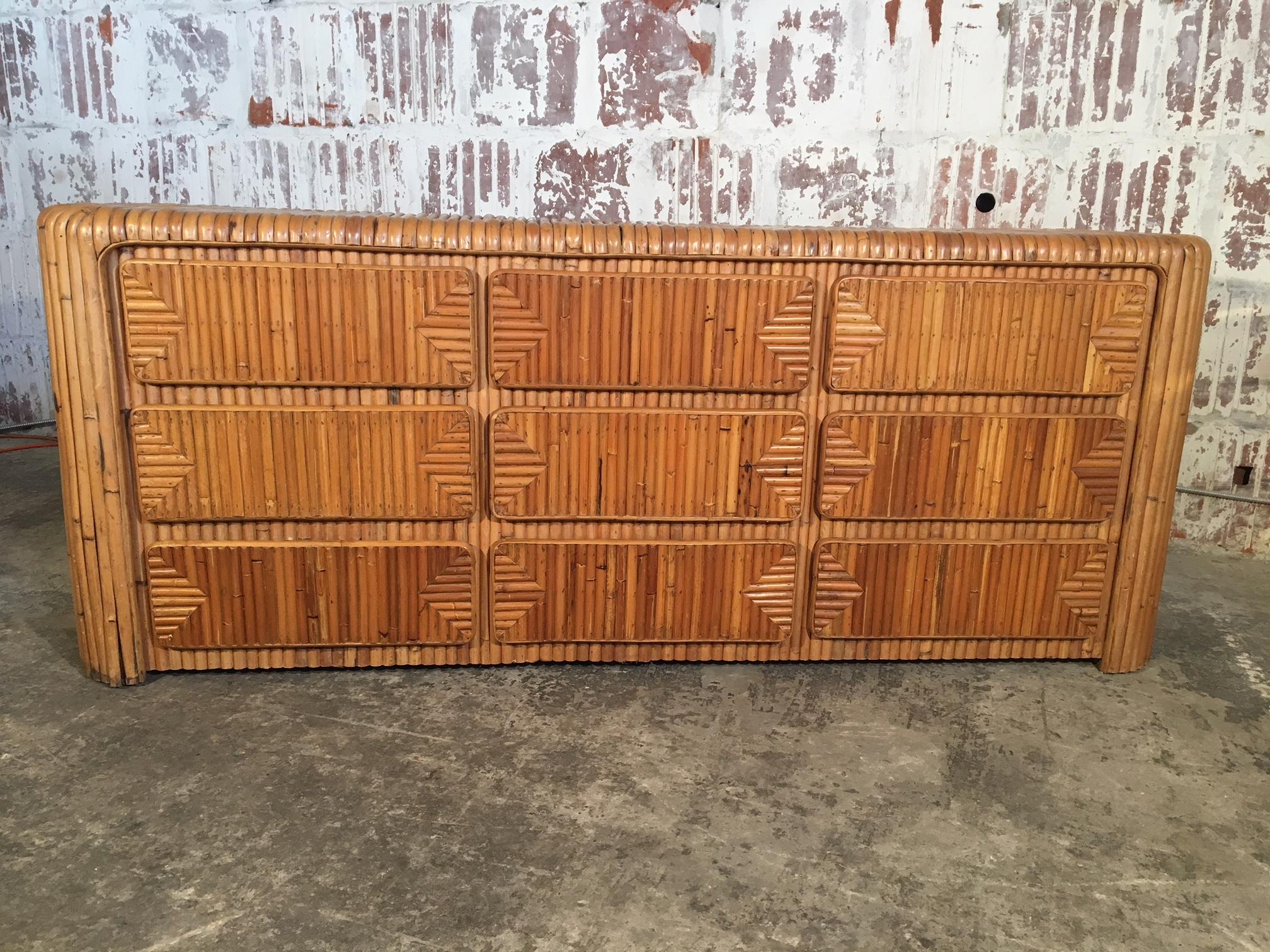 Il comò triplo in bambù con canne a spacco in stile tropicale di metà secolo presenta un design unico con intarsi in rattan e 9 cassetti. Condizioni vintage molto buone con usura adeguata all'età. I cassetti funzionano senza problemi grazie alle