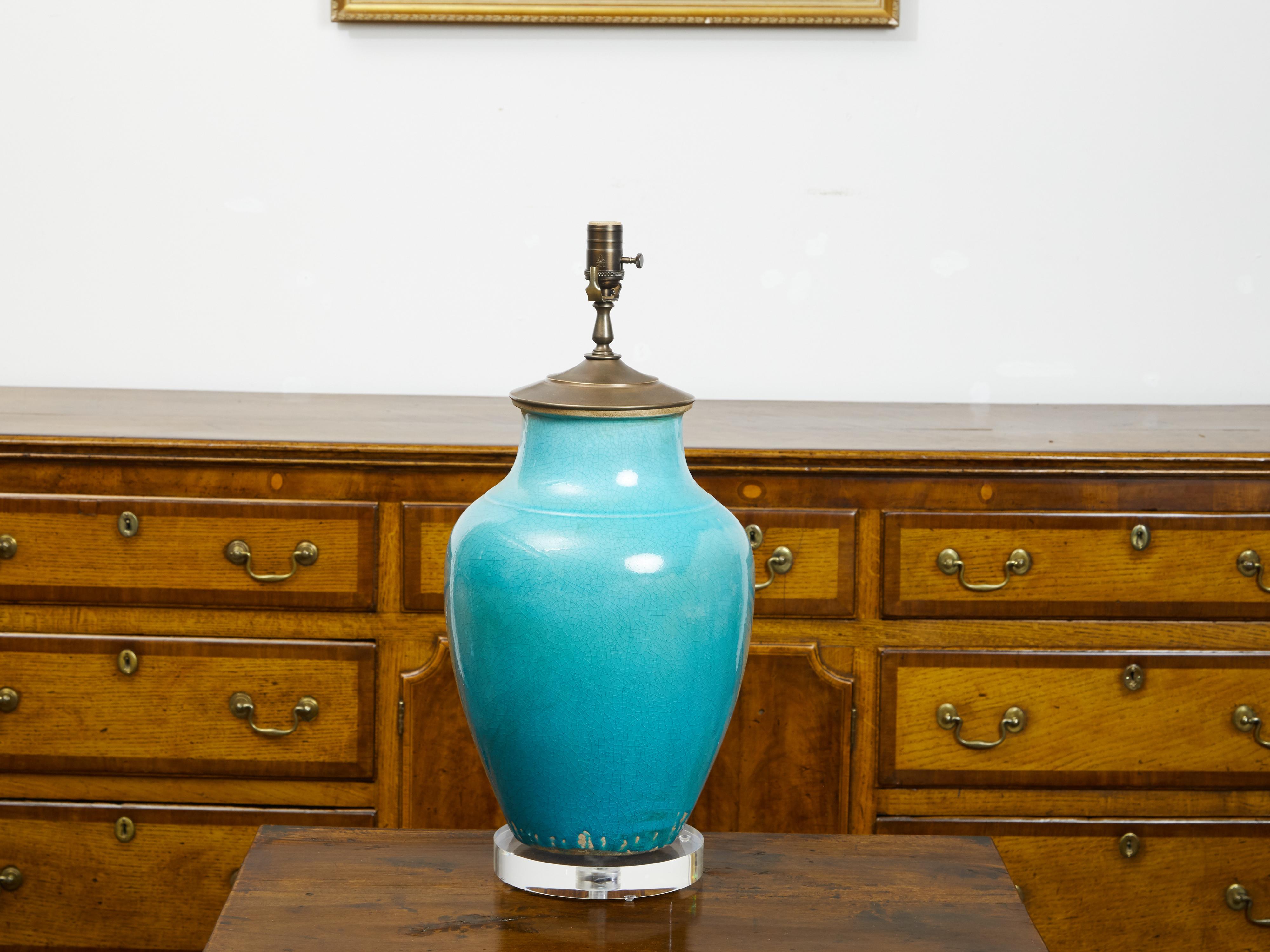 A turquoise Asian table lamp from the mid 20th century, with lucite base. Created during the midcentury period, this table lamp draws the attention with its turquoise glazed ground perfectly complimenting the purity of its lines. Raised on a