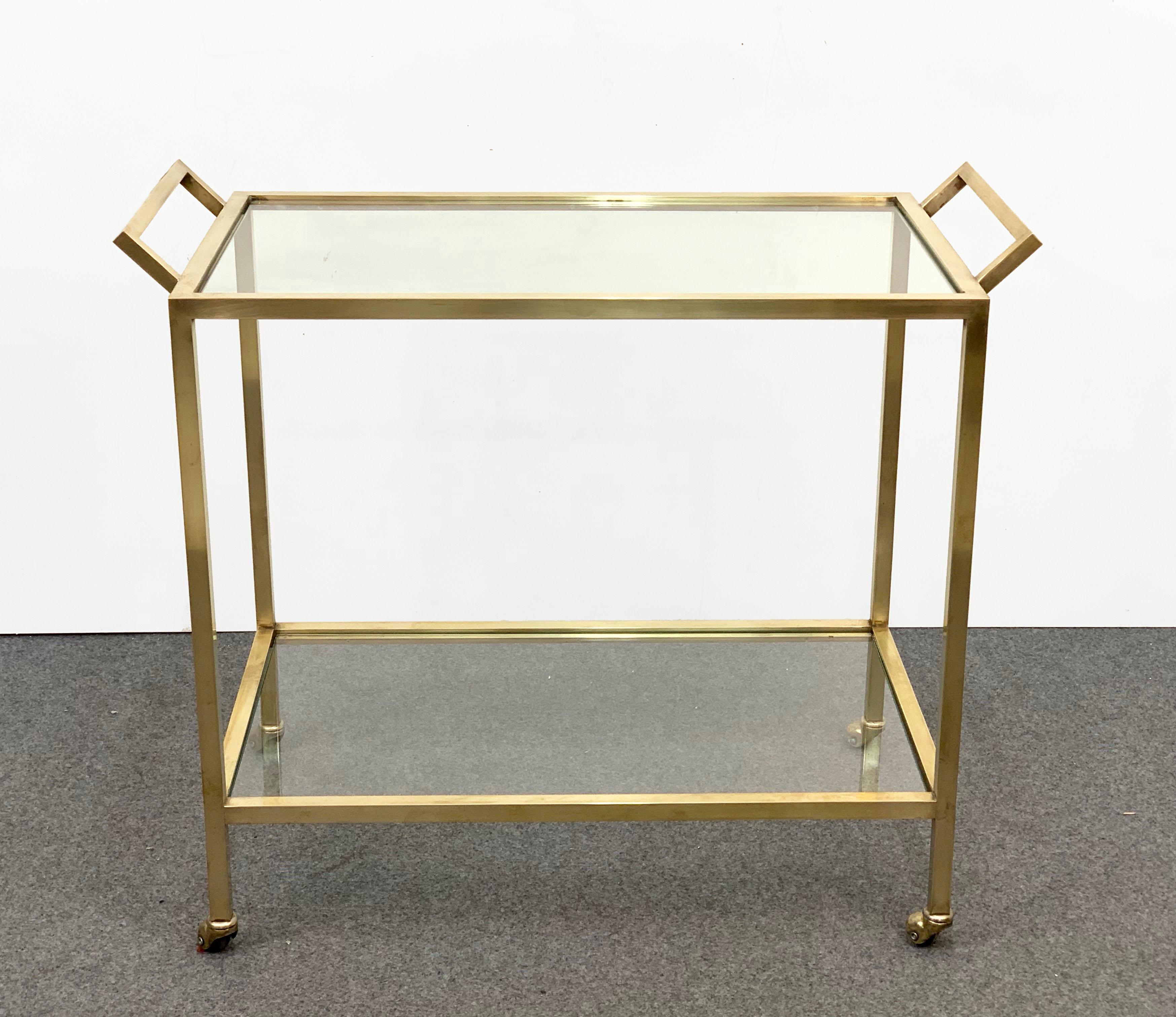 Exceptional two-level service midcentury brass cart produced in Italy during 1970,

The brass is gold-plated, the tiny wheels and the cristal glass, with a perpendicular design, represent Italy during the 1970s at its best.

A magnificent piece