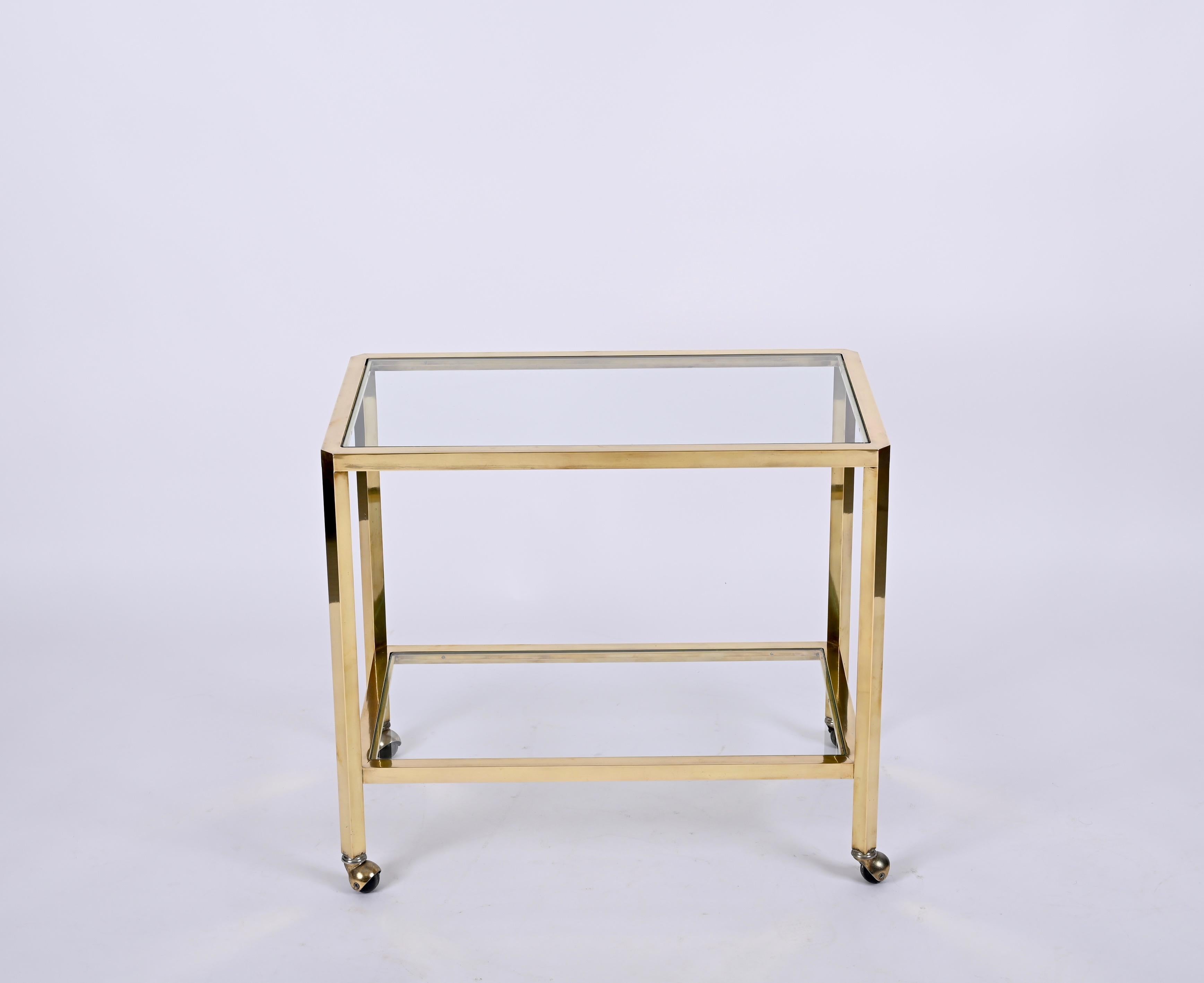 Exceptional two level mid-century service cart in brass. This gorgeous piece was produced in Italy during 1970.

This stunning bar cart features a structure made in gold-plated brass and the two original crystal glasses. An incredibly charming