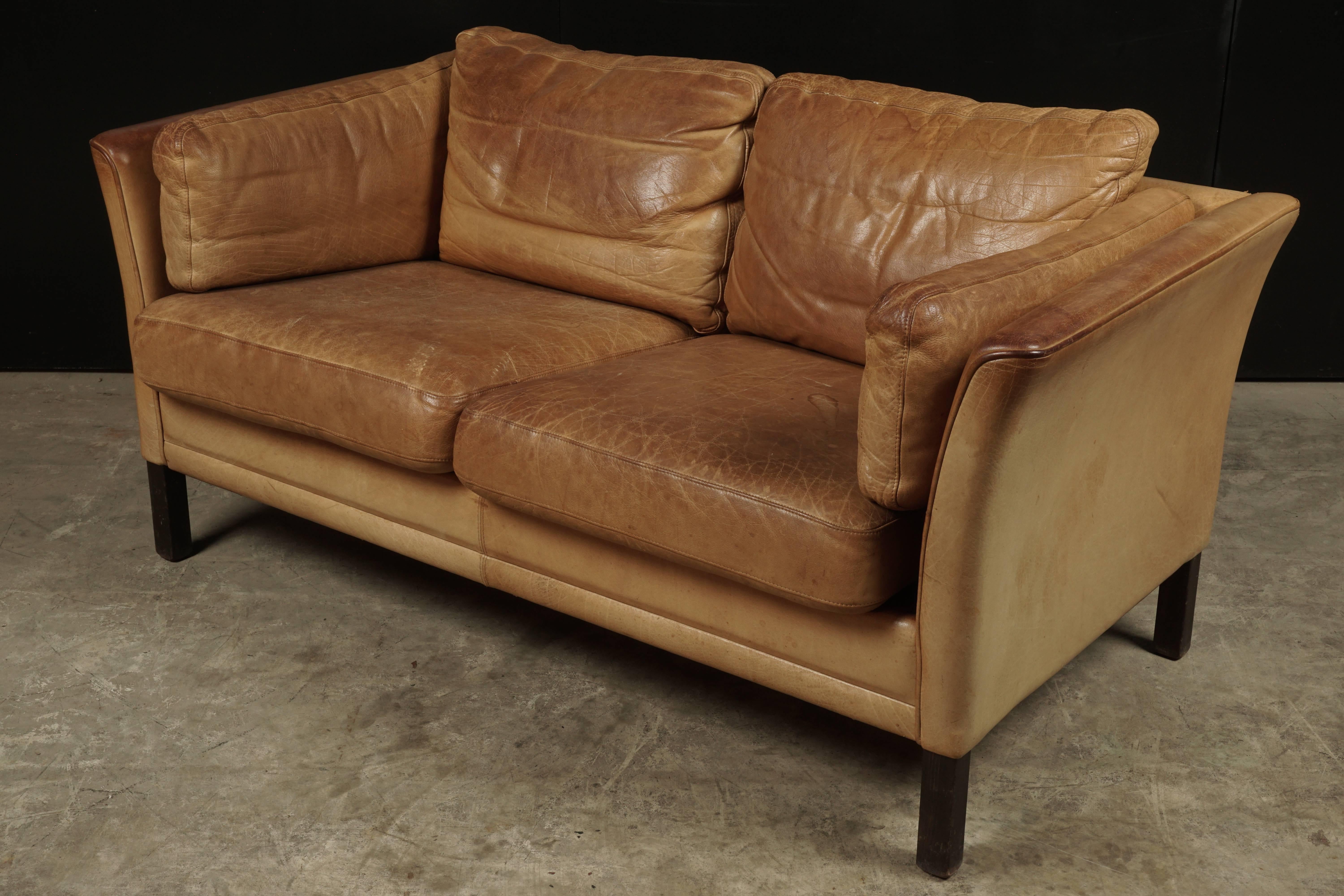 Midcentury two-seat sofa from Denmark, circa 1970. Original cognac leather upholstery with solid stained birch feet.