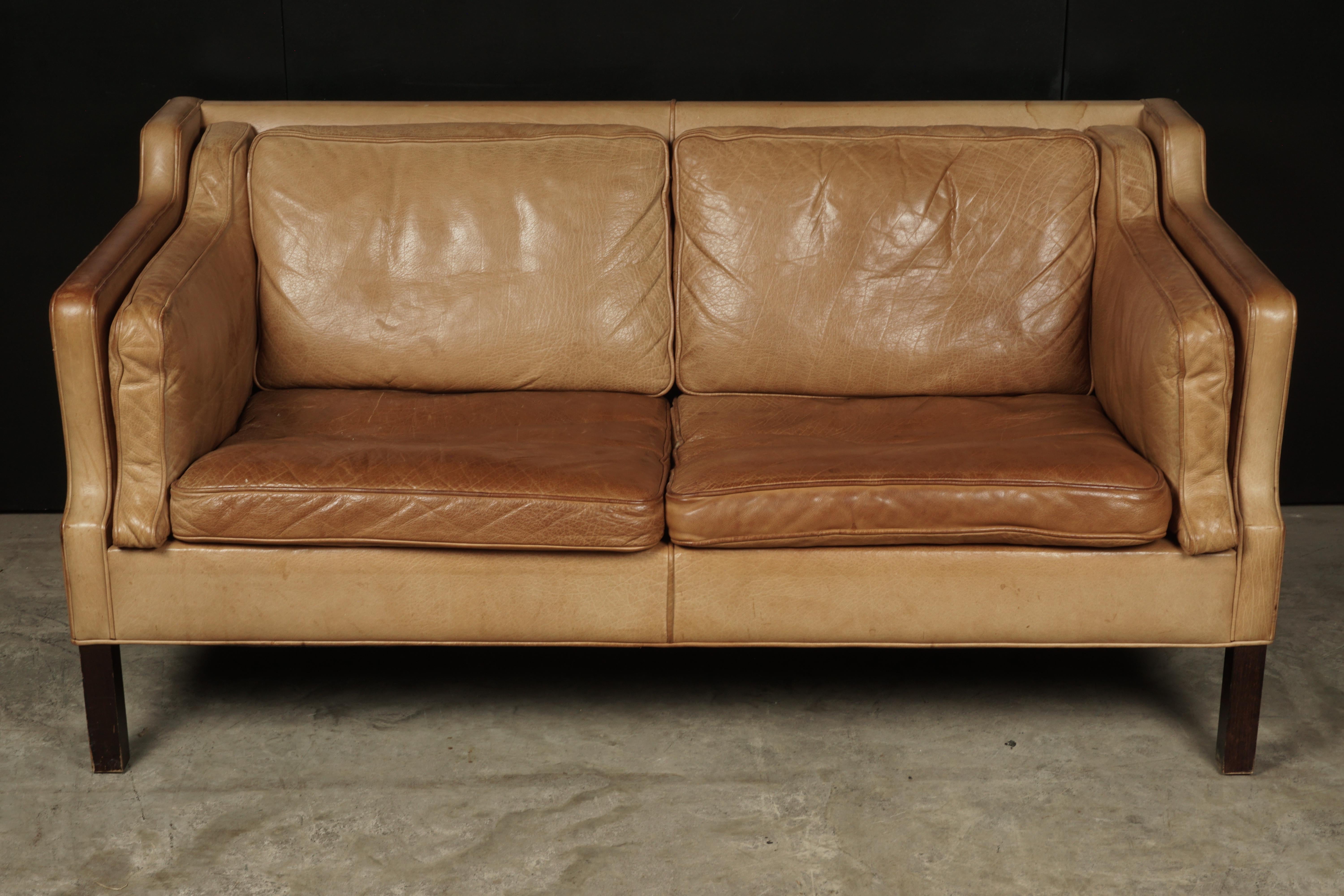 Midcentury two-seat sofa from Denmark, circa 1970. Original tan leather upholstery with nice patina and wear.