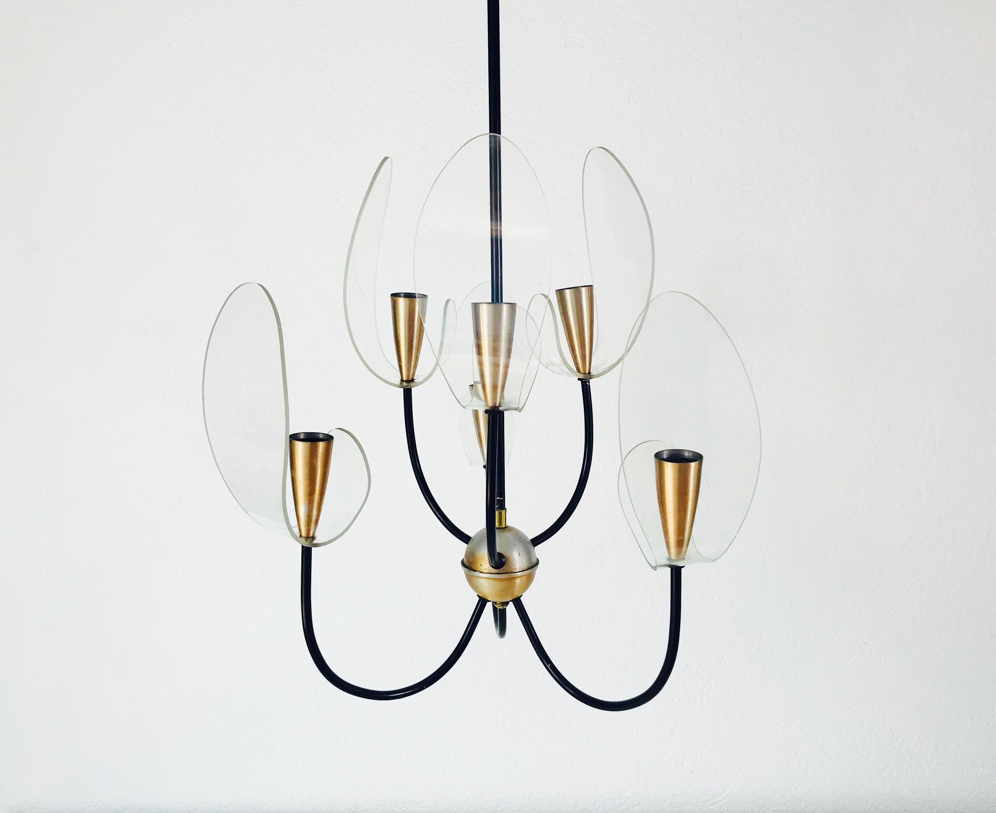 A mid century chandelier made in Italy in the 1960s. It is fascinating with its rare arms, each of with a copper bulb socket and a acrylic glass shade. The body is also made of metal and copper. The shape of the light is similar to the lamps of